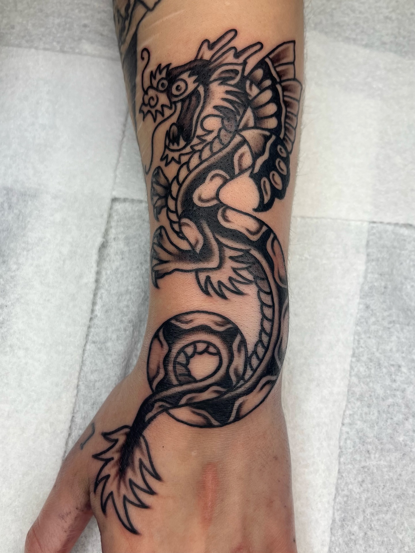 Dragon black and grey tattoo on the forearm by Macy Bird