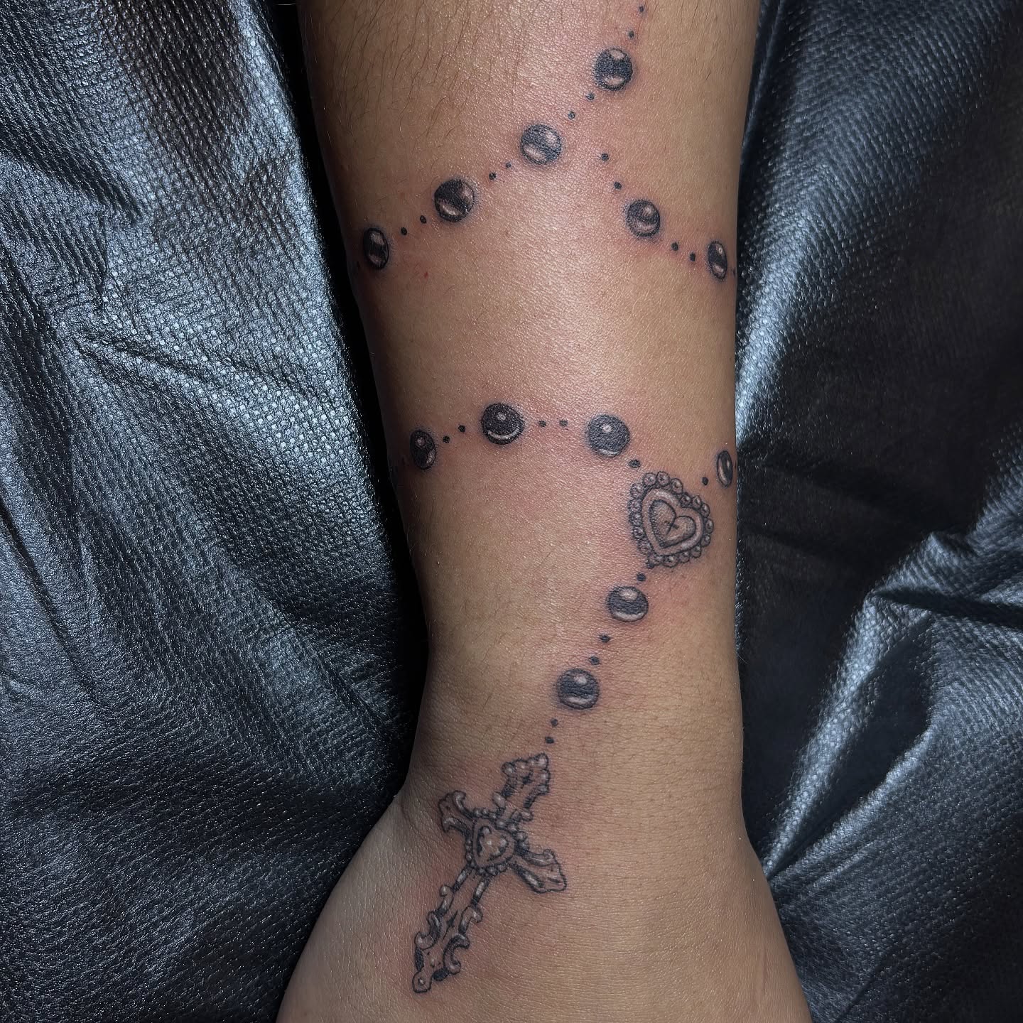 Rosary dotwork tattoo on the forearm by Sydney Gallucci