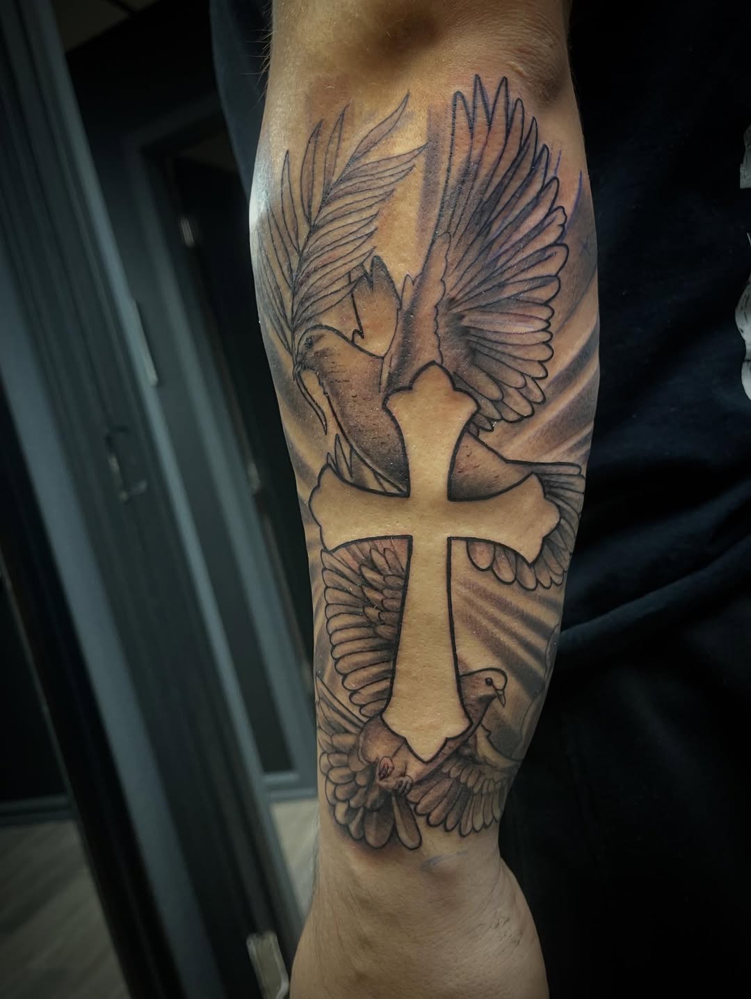 Cross with doves realism tattoo on the forearm by Chris Torres