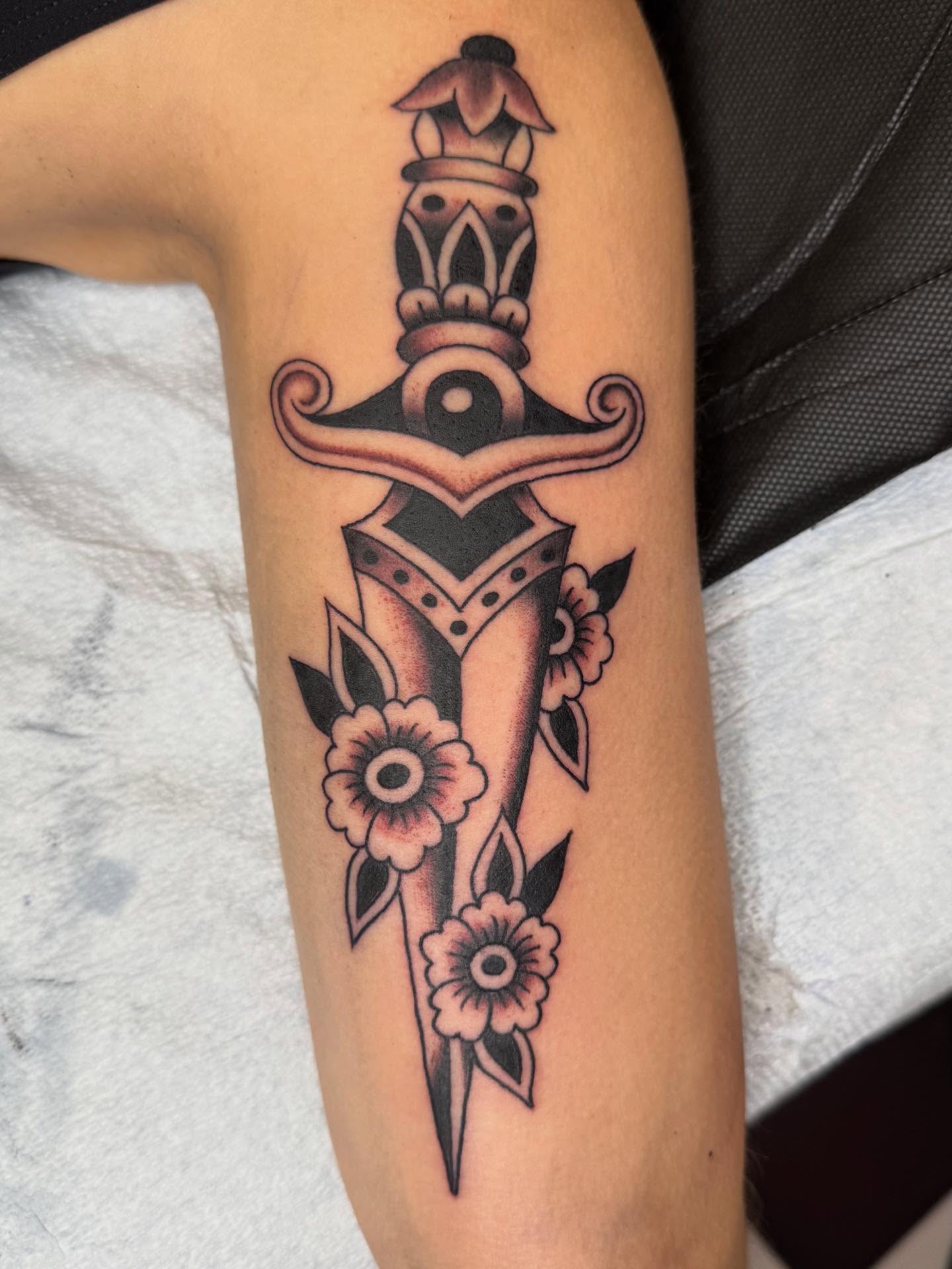 Sword and flowers American traditional tattoo on the forearm by Emma Eaton