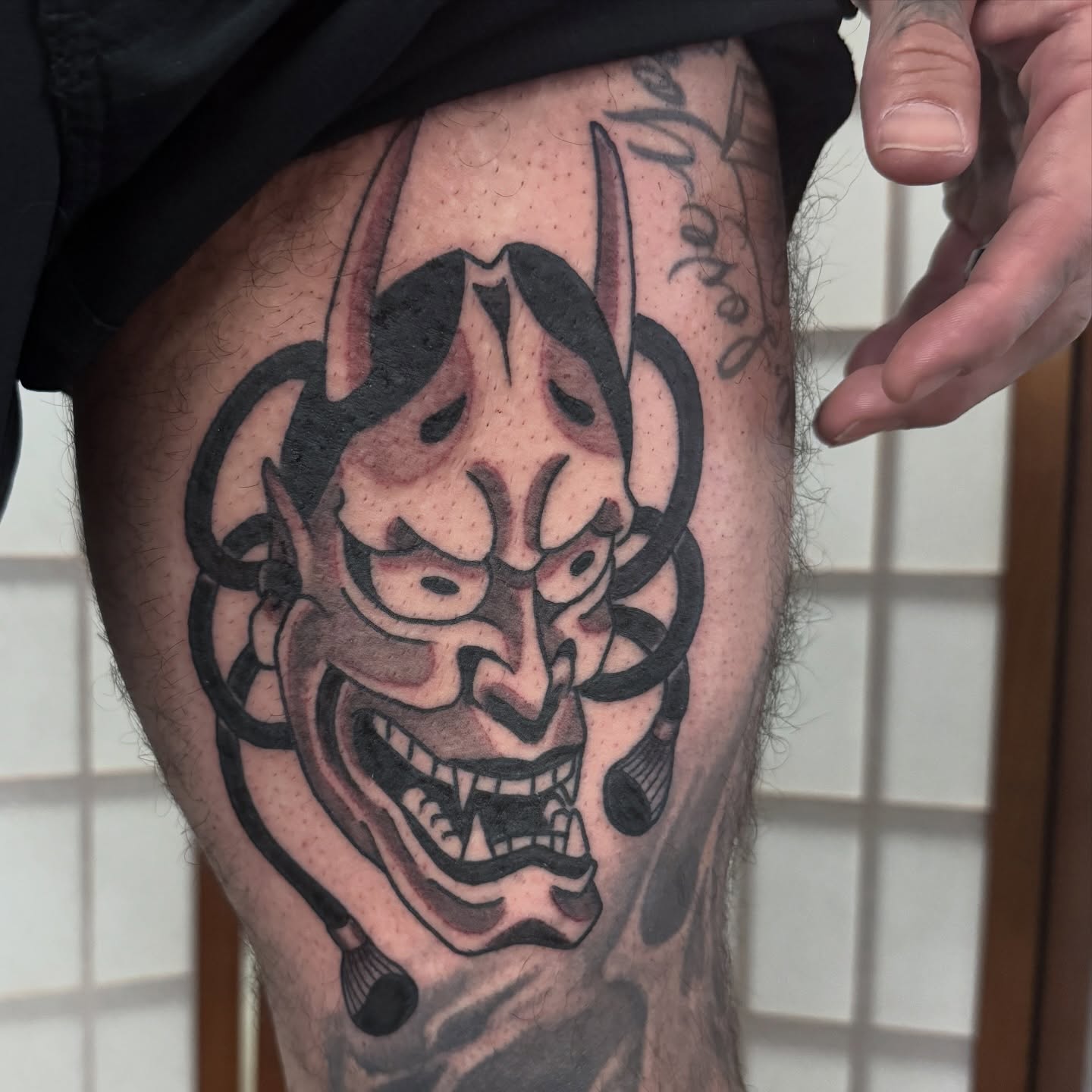 Demon mask black and grey tattoo on the thigh by Dylan