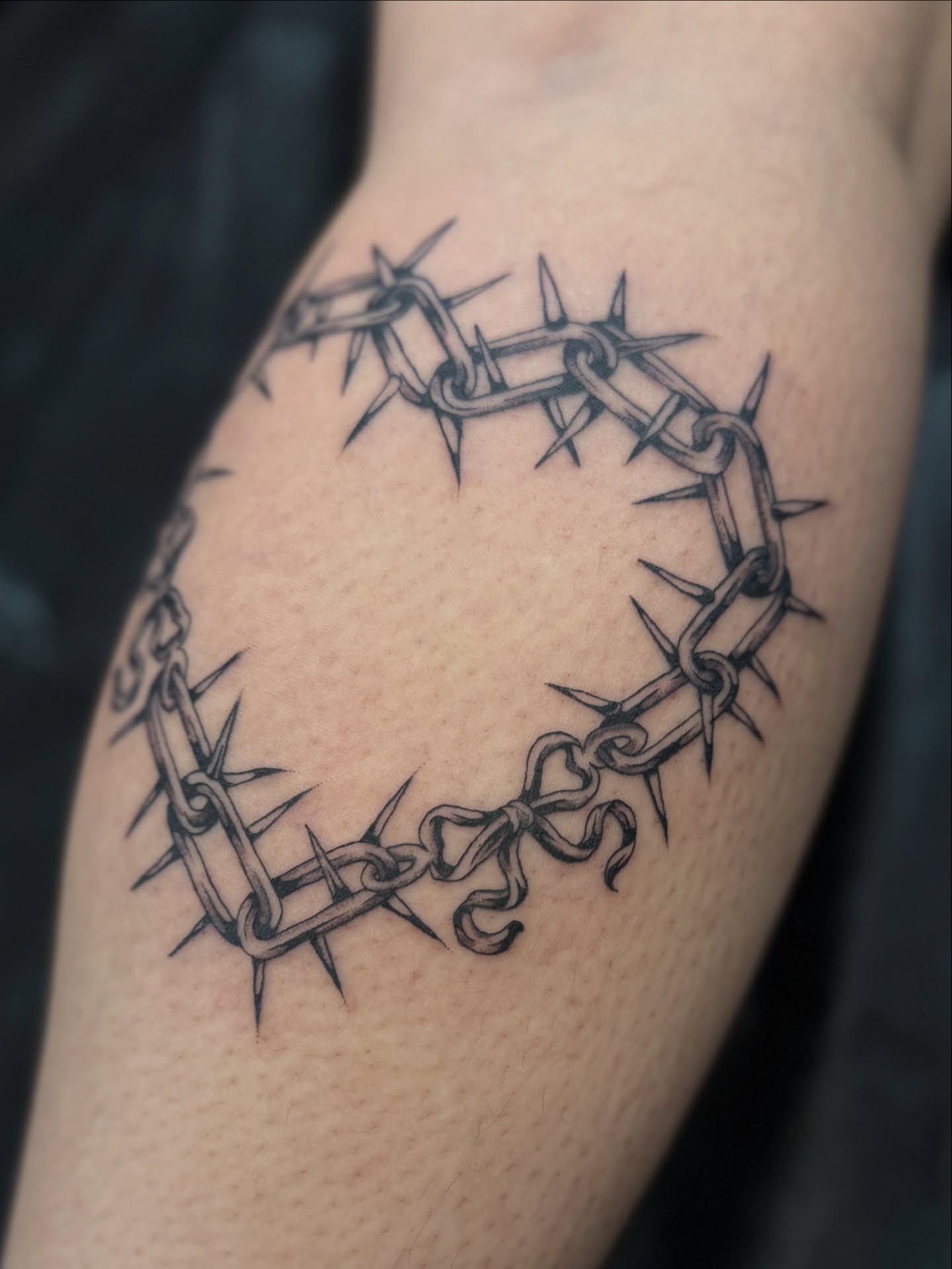 Barbed wire crown black and grey tattoo on the forearm by Sarah Pham
