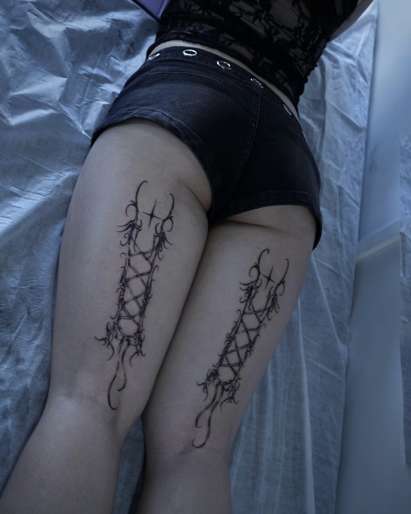 Corset lacing black and grey tattoo on the thigh by Gun