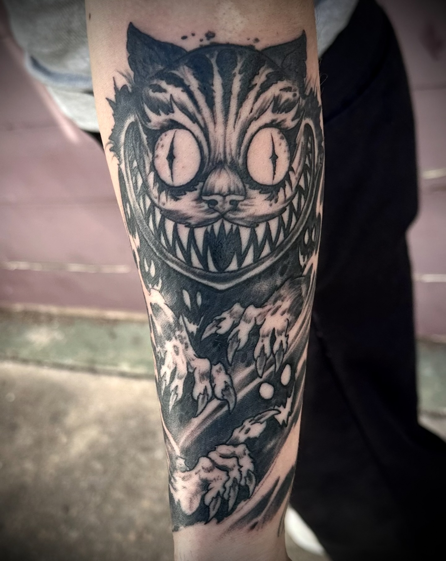 Cheshire cat black and grey tattoo on the forearm by Culleton Paramore