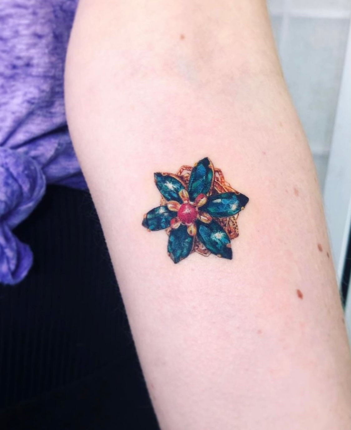 Gemstone flower geometric tattoo on the forearm by Alissa Jung
