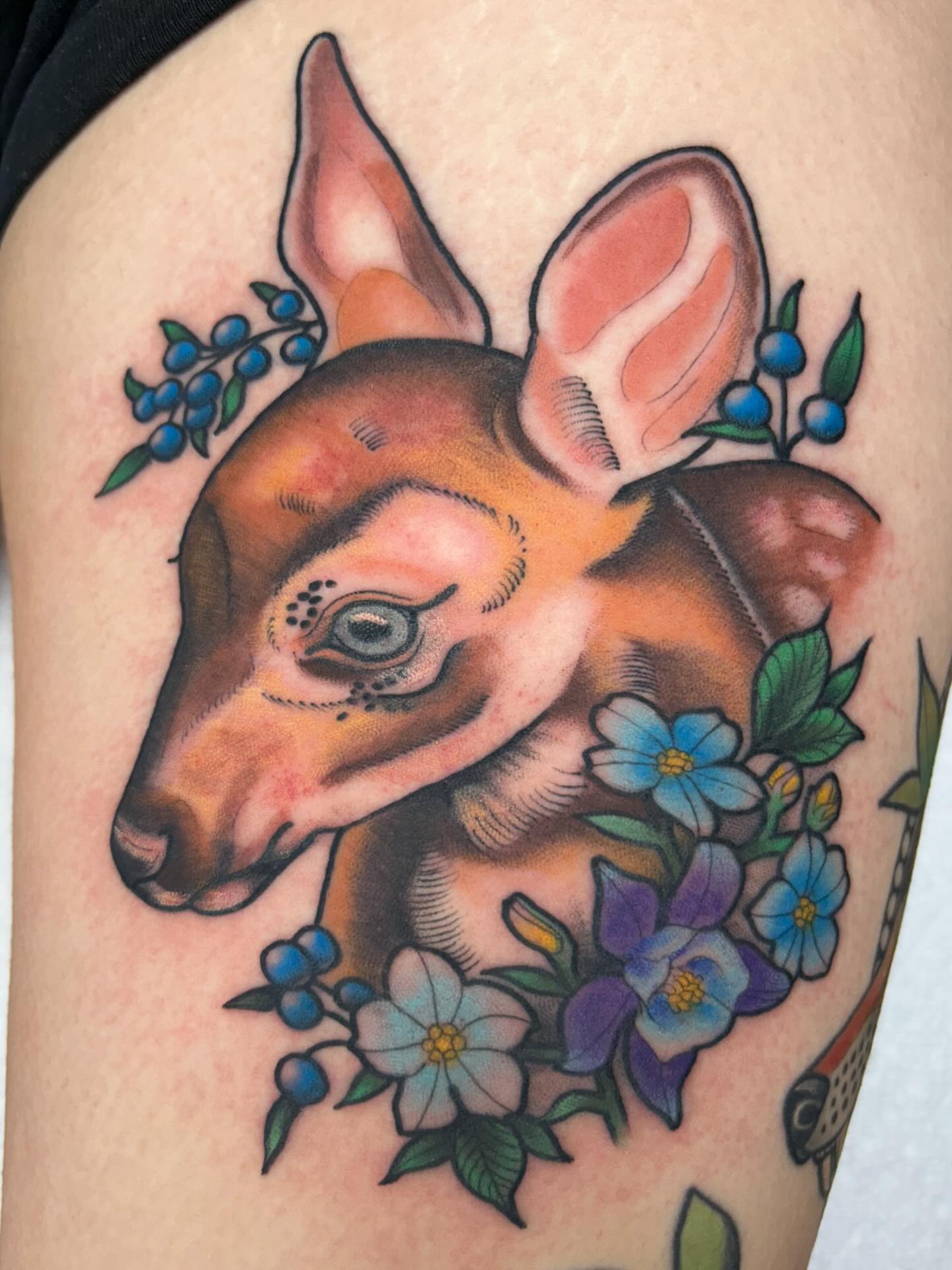 Deer head with flowers American traditional tattoo on the thigh by Tiffany Vargas