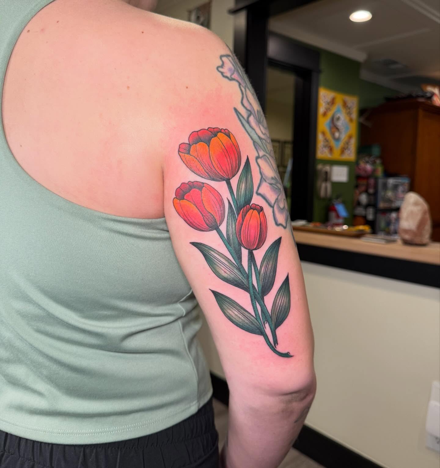 Tulips new school tattoo on the upper arm by Rebecca Basma Smith