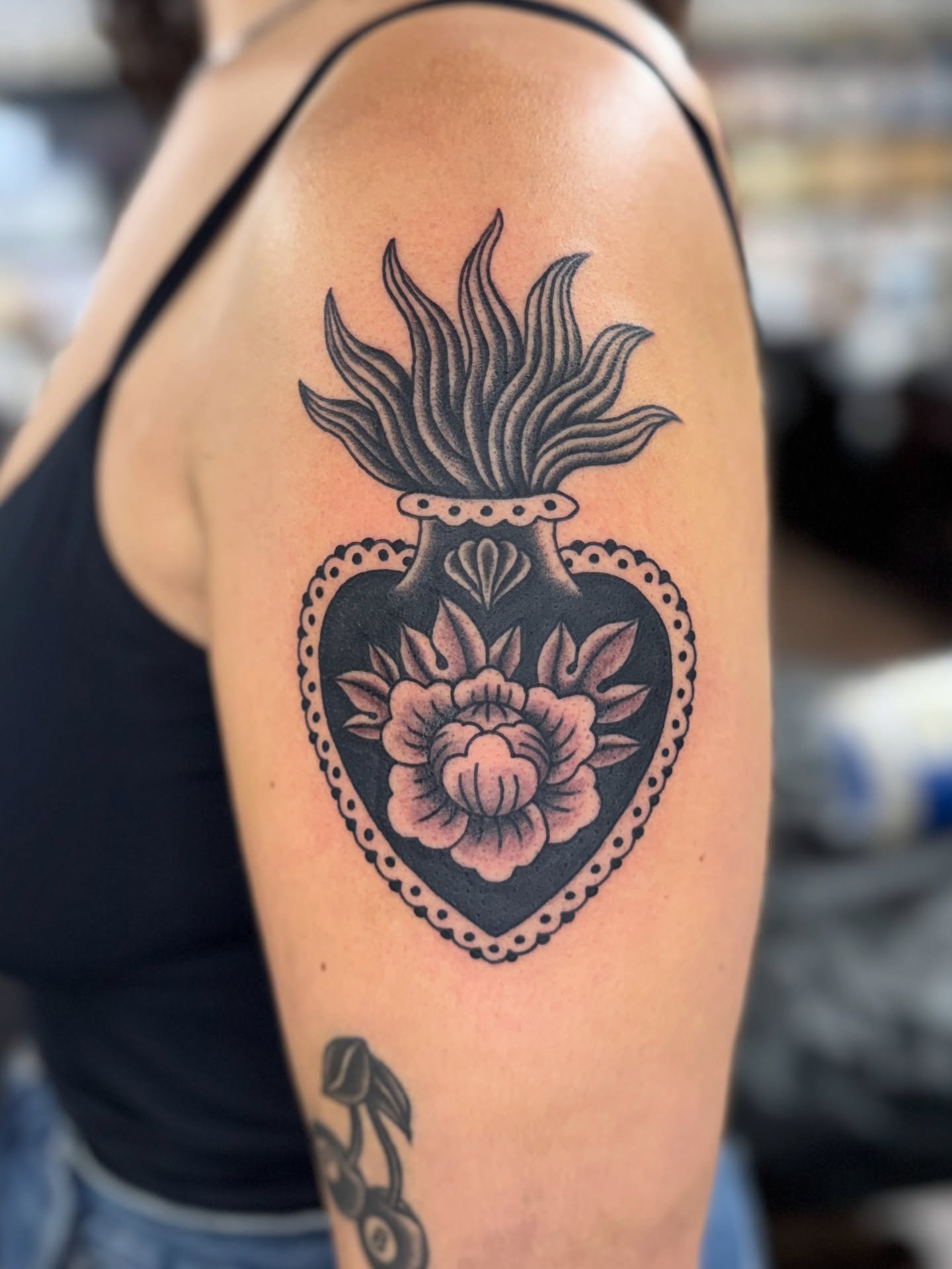 Heart with flower American traditional tattoo on the upper arm by Sarah Pham