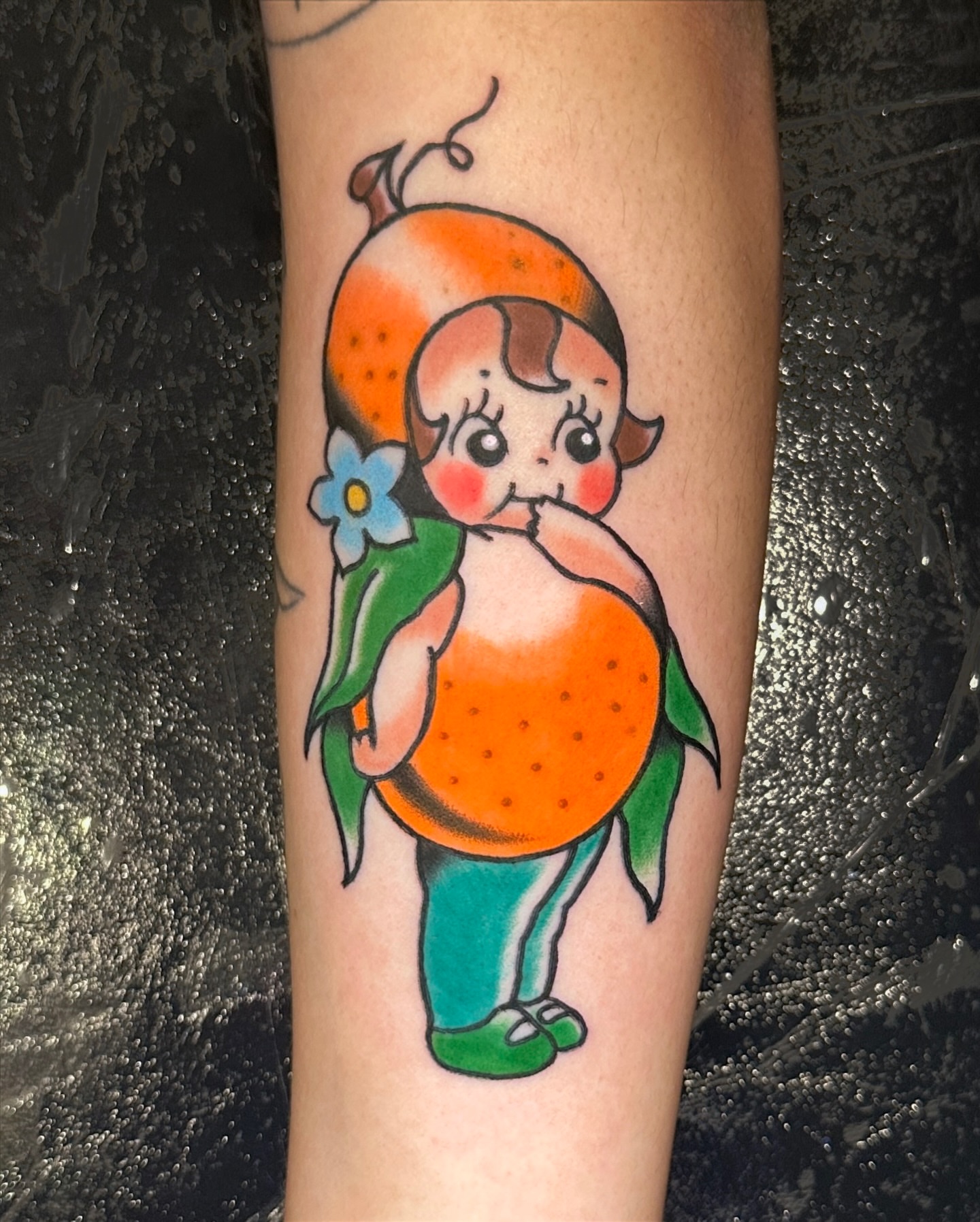 Child with orange American traditional tattoo on the forearm by Paige Ochoa