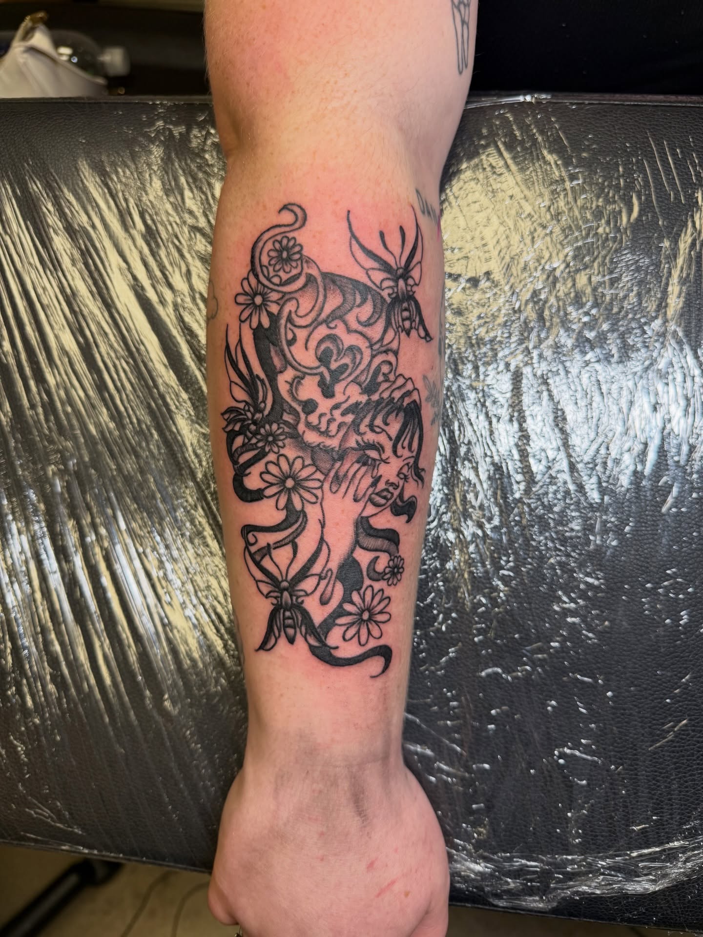 Skull and flowers black and grey tattoo on the forearm by Humberto Vega