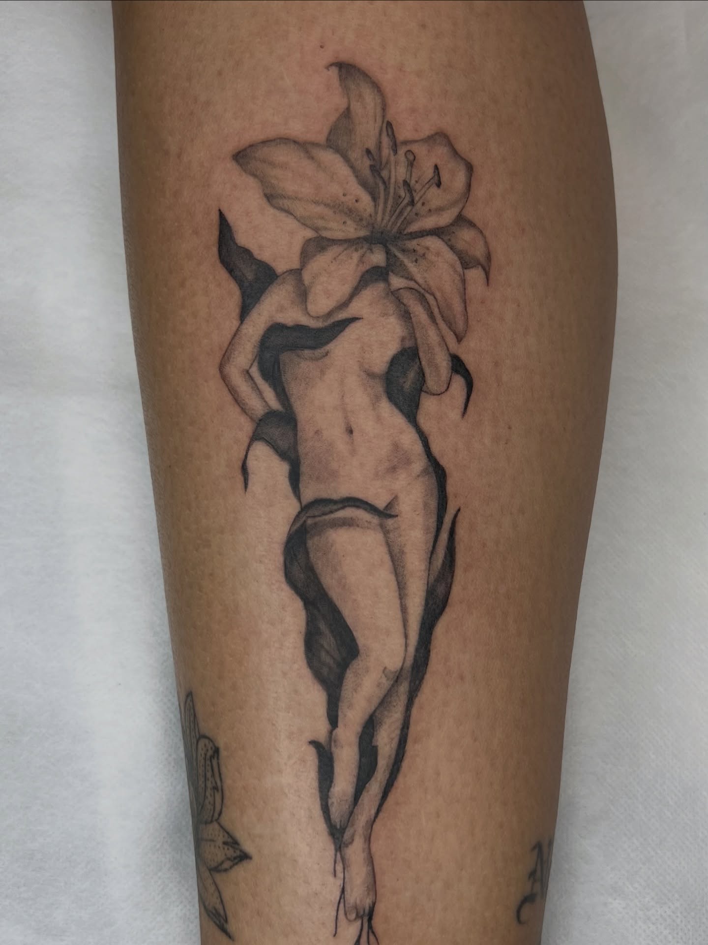 Nude figure with lily realism tattoo on the leg by Red