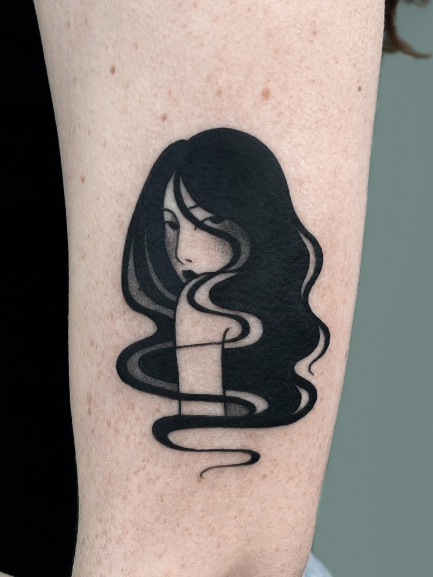 Woman with flowing hair black and grey tattoo on the forearm by nina