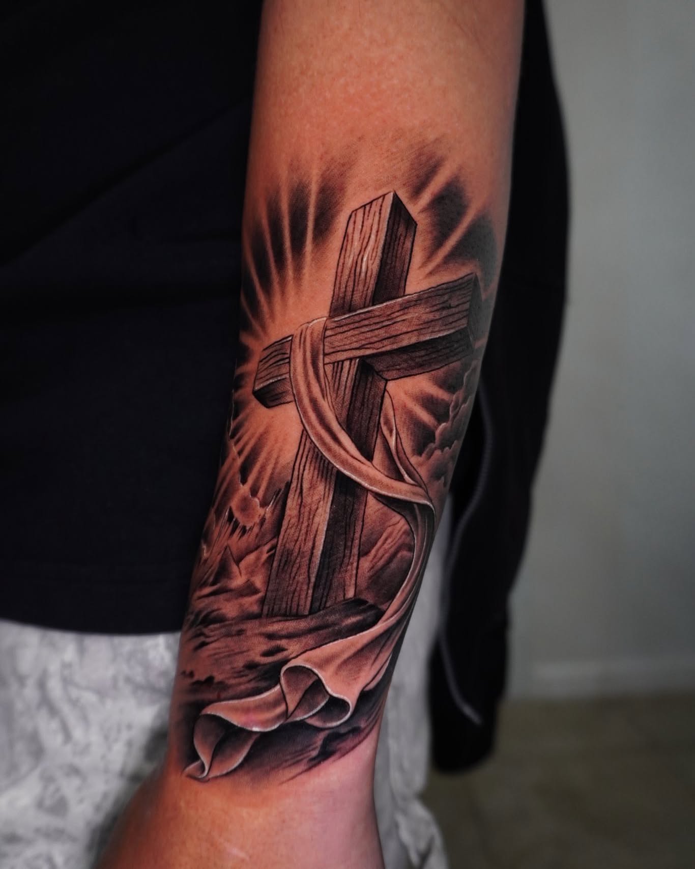 Cross with ribbon realism tattoo on the forearm by Ayala Jose