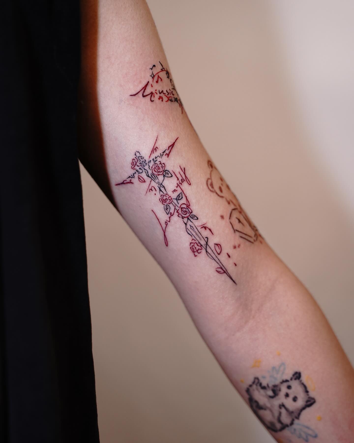 Floral cross fine line tattoo on the forearm by Tomato