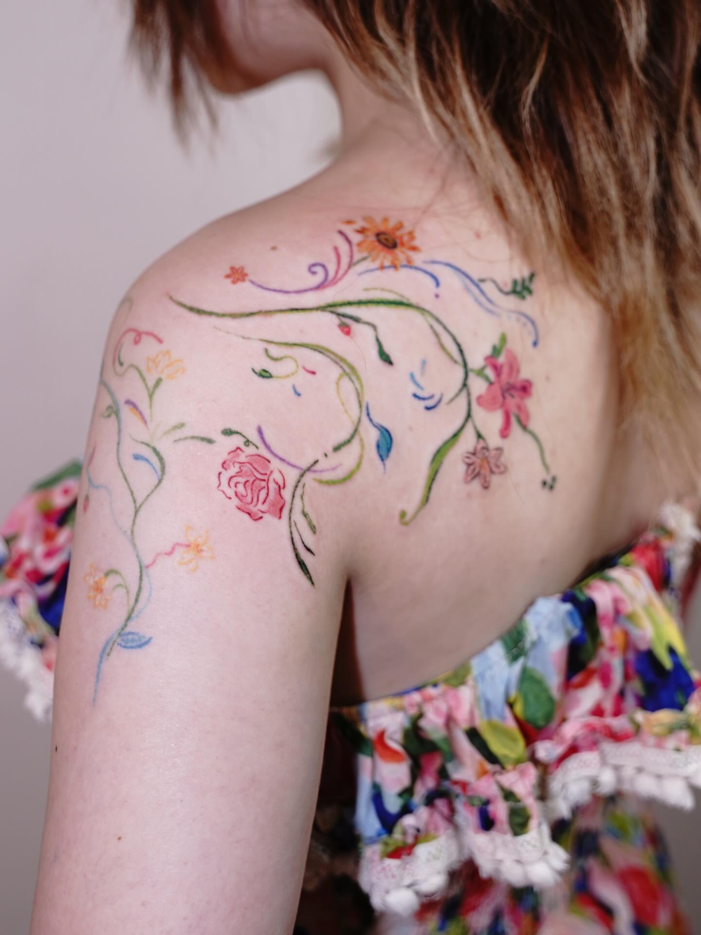 Floral vine watercolor tattoo on the shoulder by Tomato