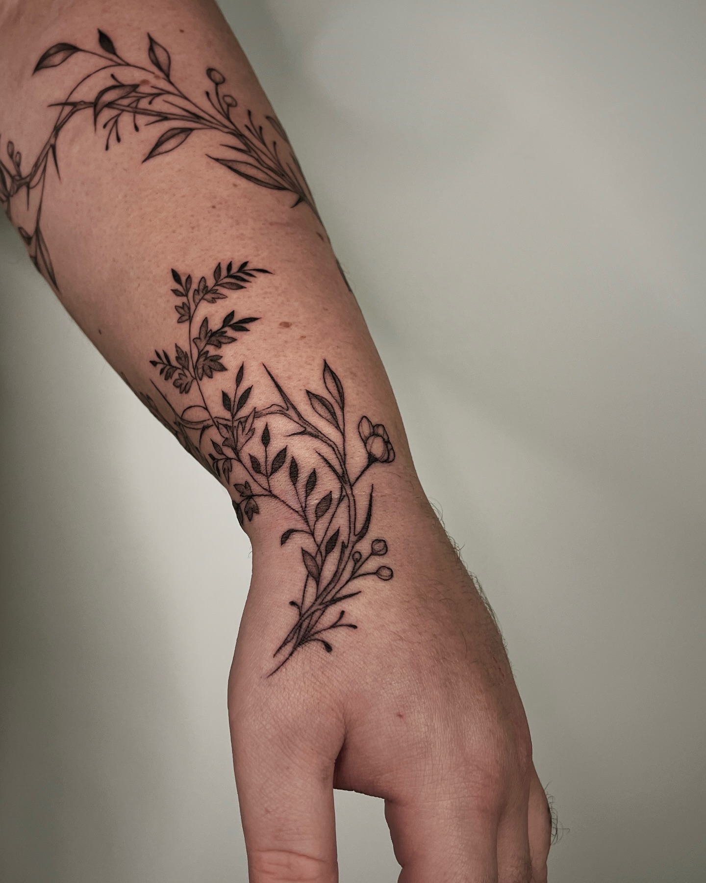 Botanical black and grey tattoo on the forearm by Mikayla Sue