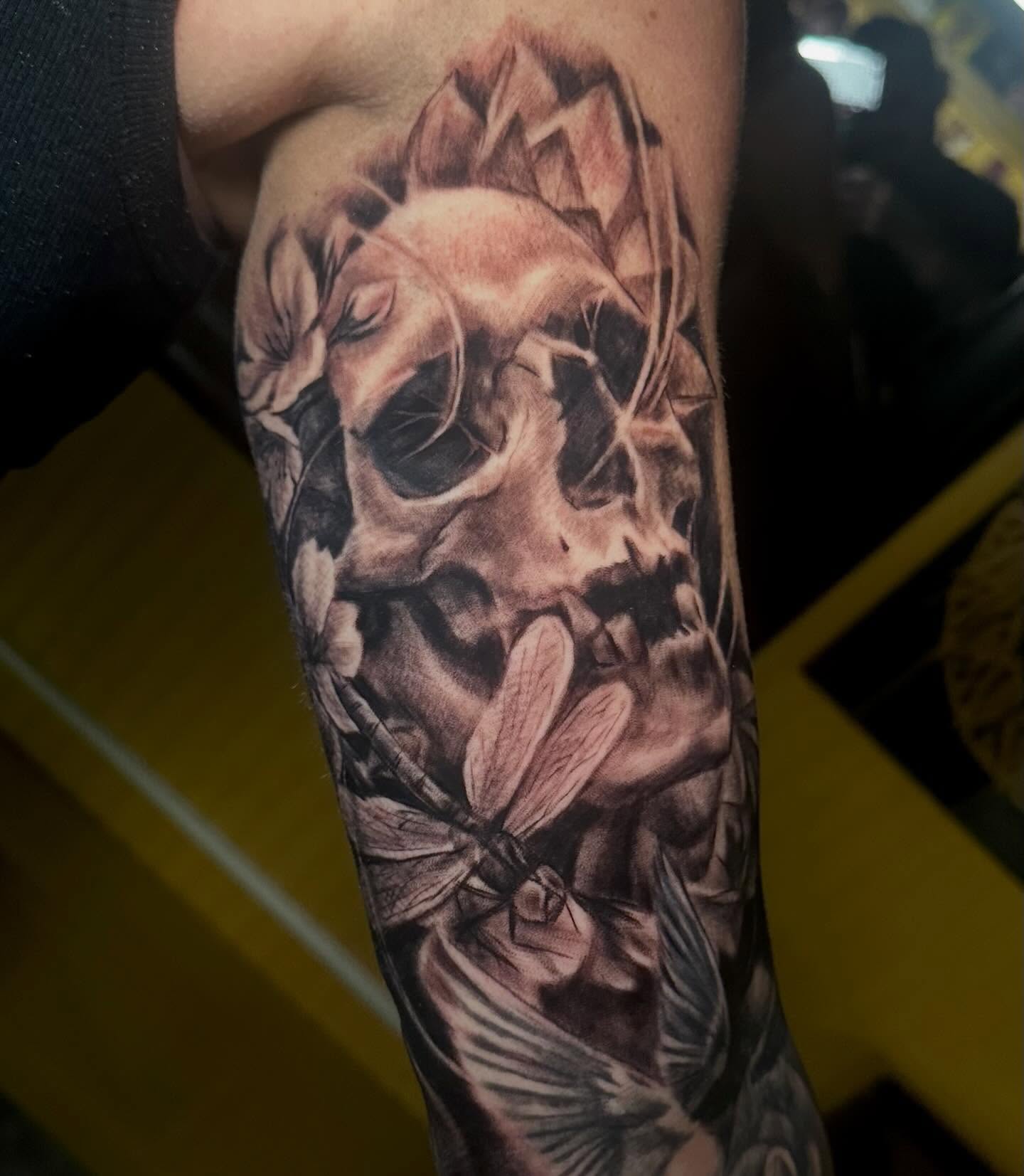 Skull and flowers realism tattoo on the forearm by Comfy Chris Fettig