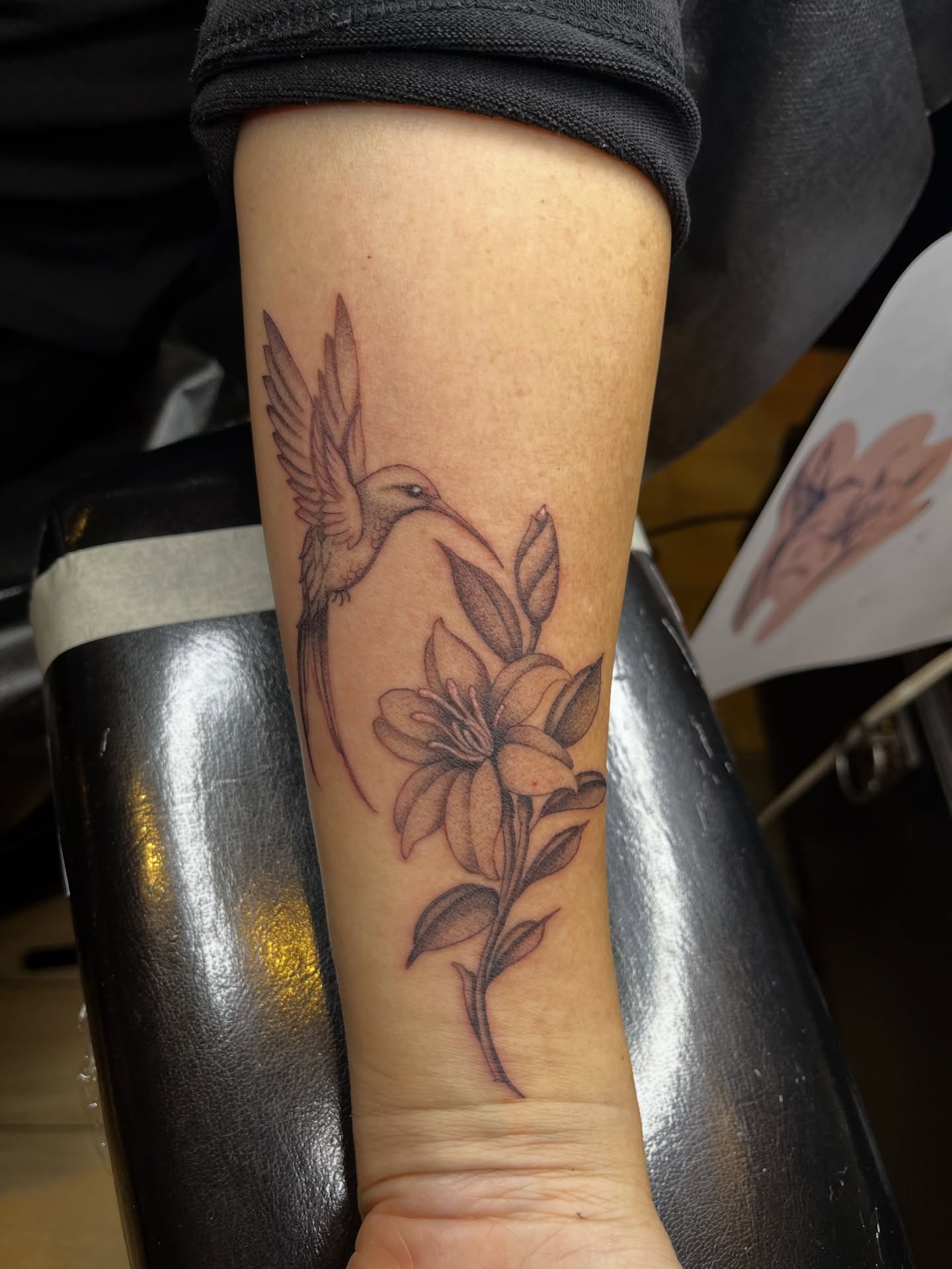 Hummingbird and flower black and grey tattoo on the forearm by Winston Thai