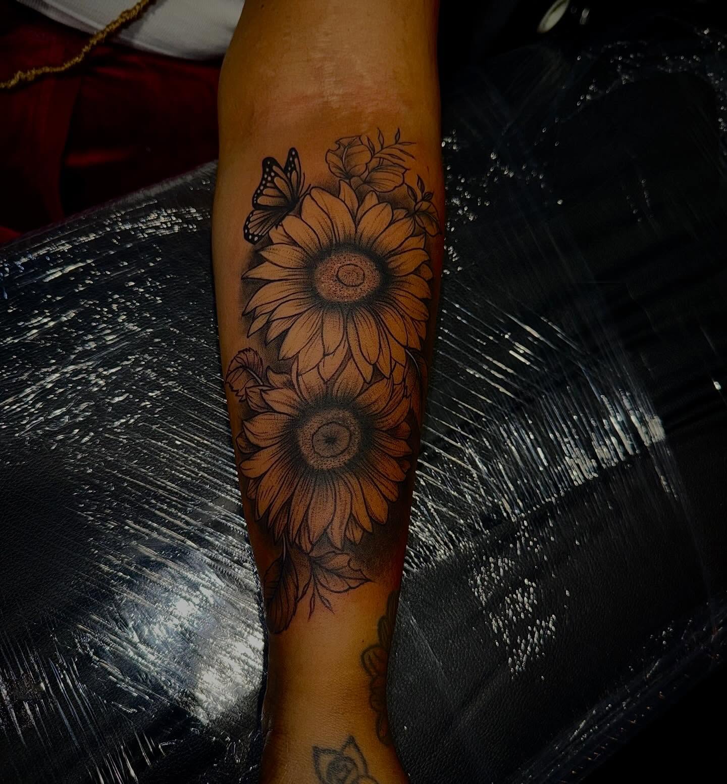 Sunflowers and butterfly black and grey tattoo on the forearm by Clifford Jordan