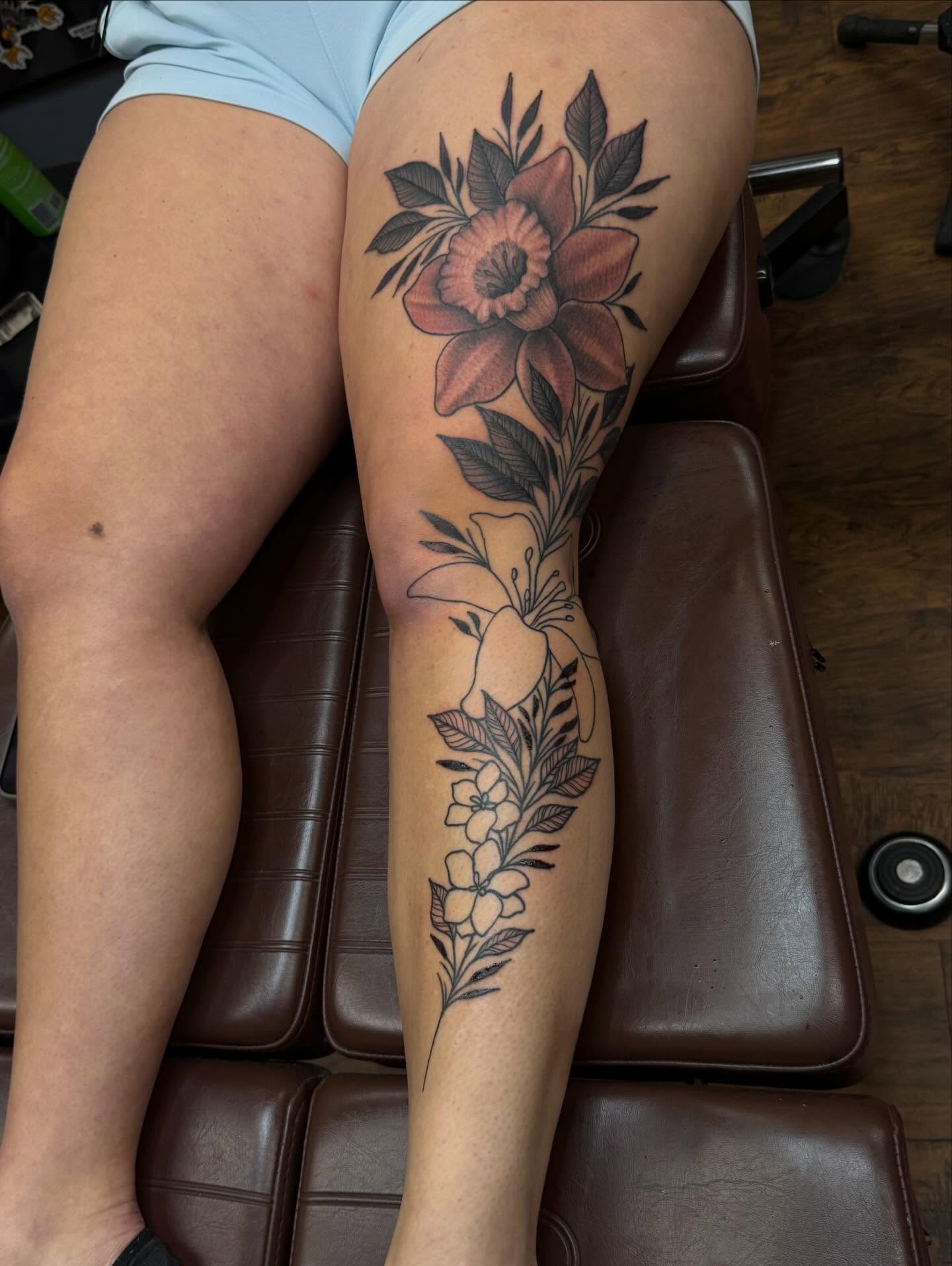 Floral arrangement black and grey tattoo on the leg by Jackie