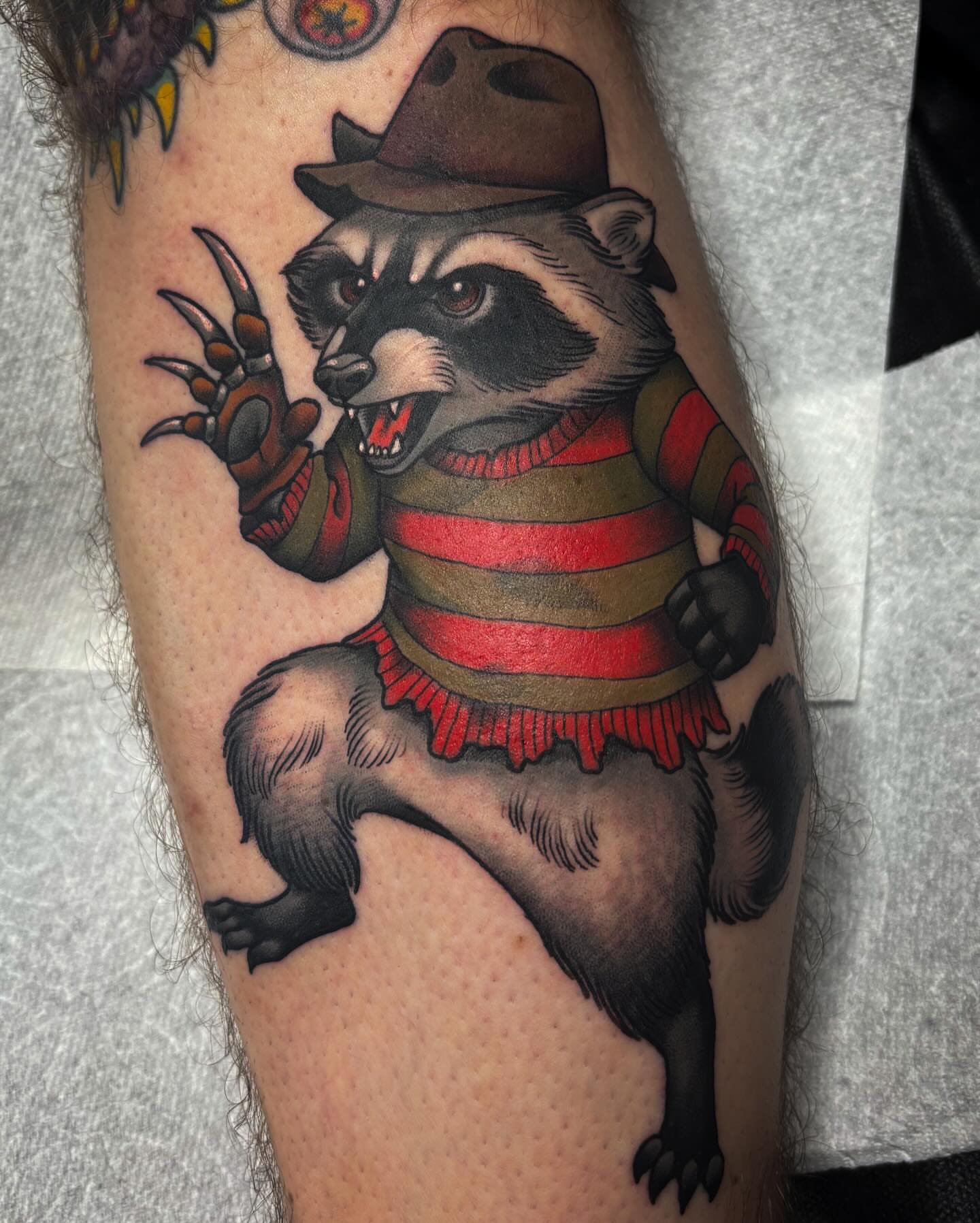 Raccoon in Freddy Krueger costume American traditional tattoo on the forearm by Monica Amneus