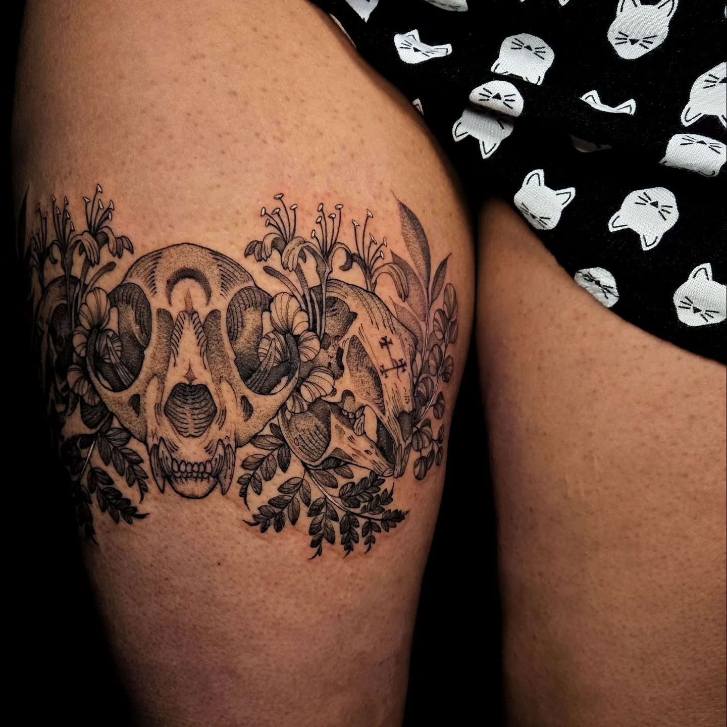 Skull and floral arrangement realism tattoo on the thigh by Jesseca Chinchilla