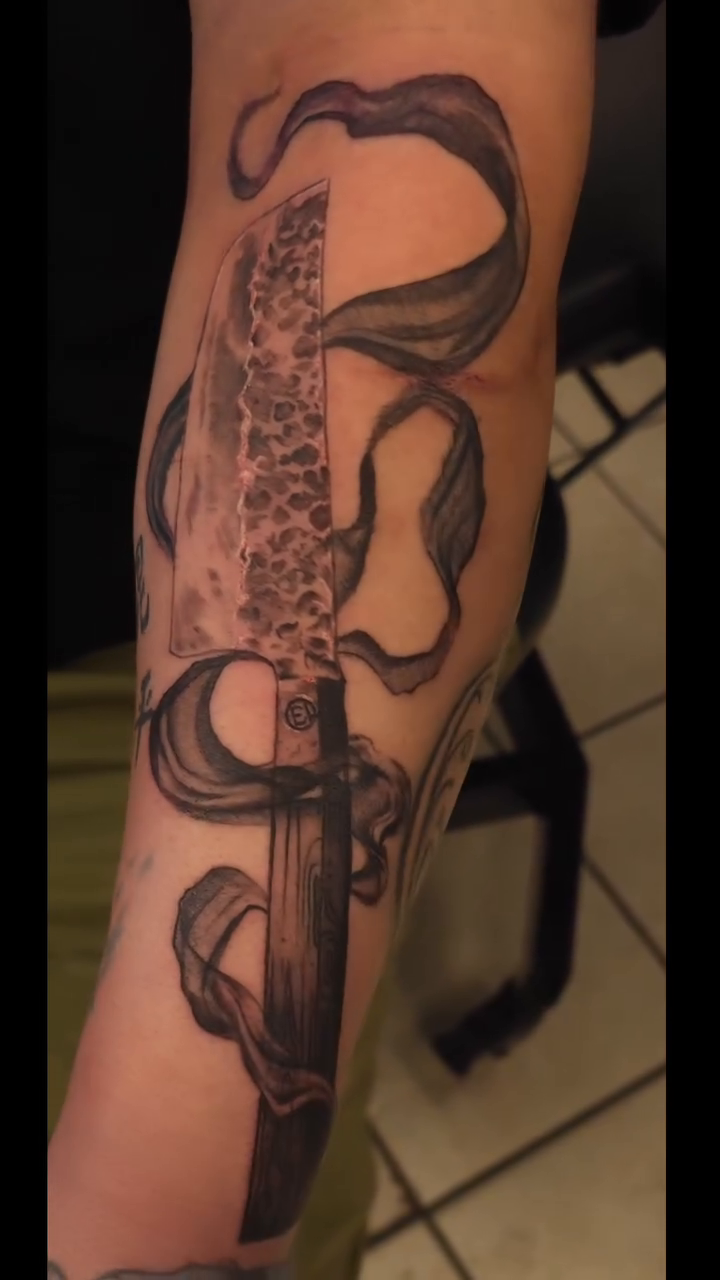 Sword with flowing ribbons American traditional tattoo on the forearm by BoogaInk
