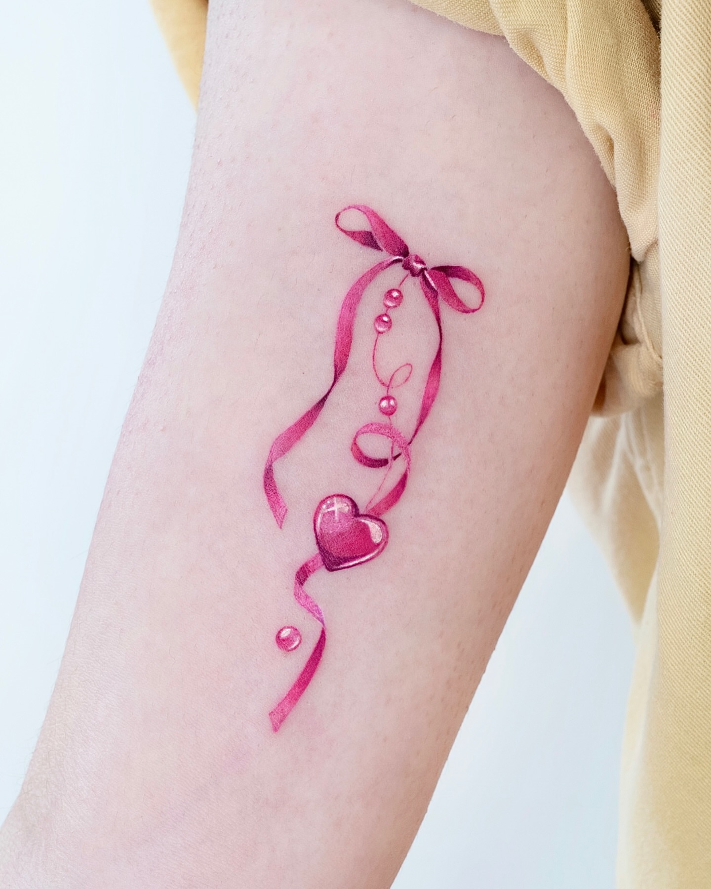 Heart with ribbon watercolor tattoo on the forearm by 라이브 Live
