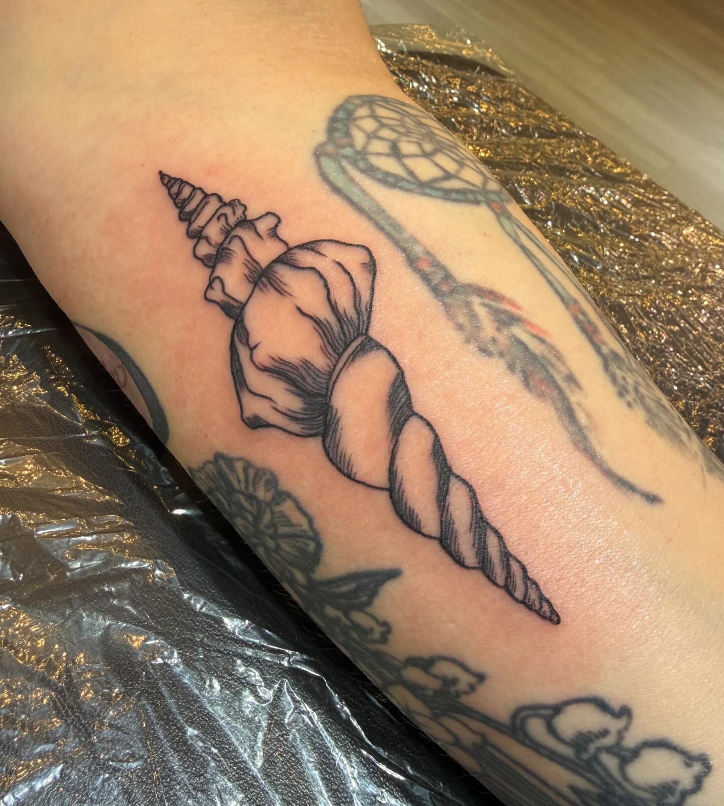 Conch shell black and grey tattoo on the forearm by Patrick Carroll
