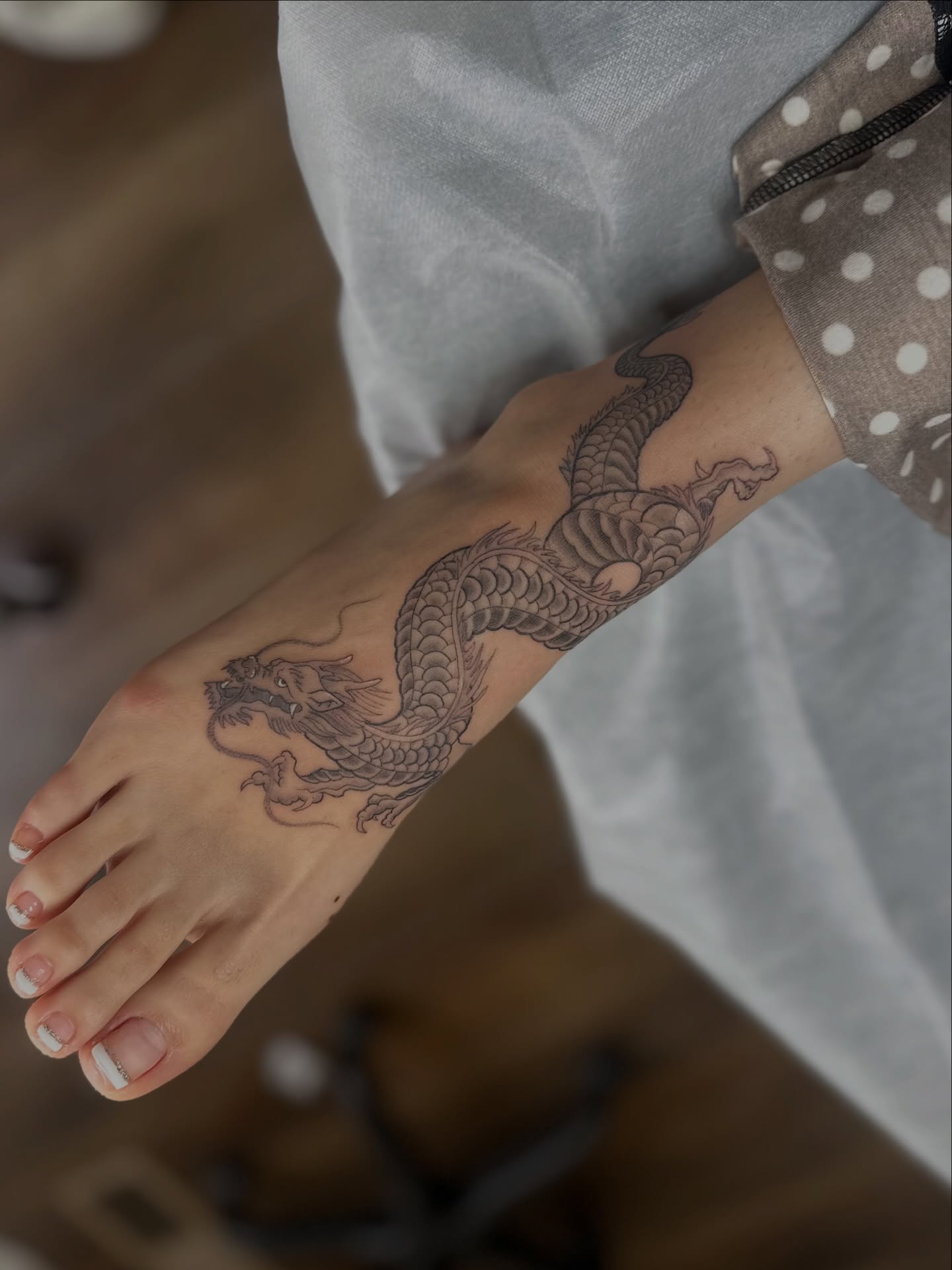 Dragon black and grey tattoo on the foot by Priscilla Michels