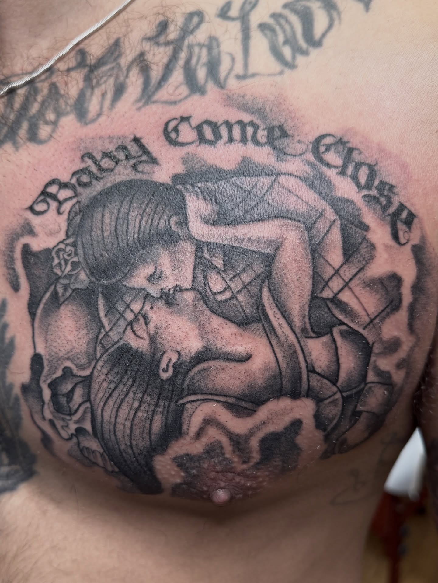 Couple kissing black and grey tattoo on the chest by Ramón Silva