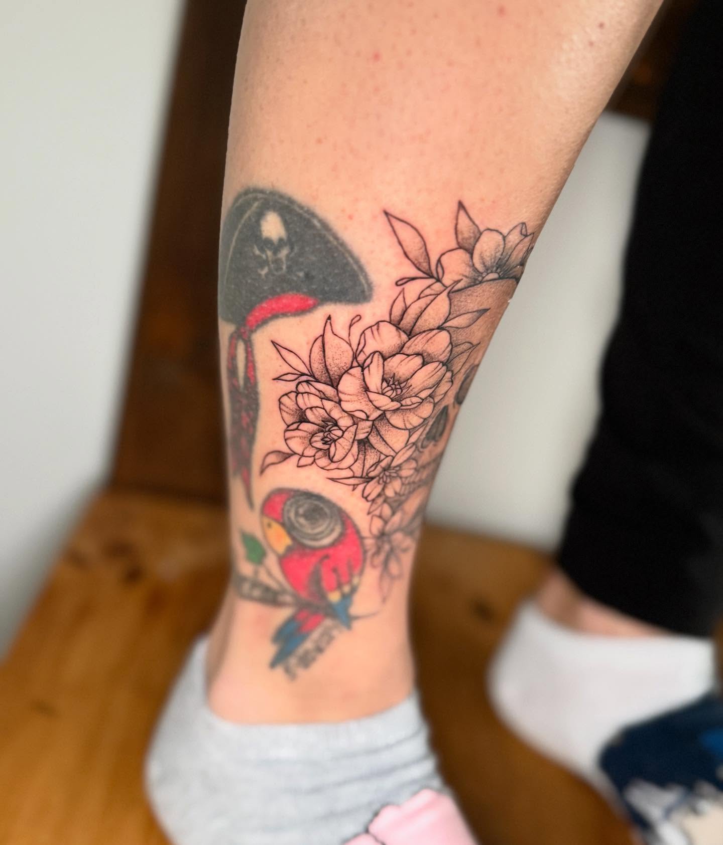 Parrot and flowers American traditional tattoo on the forearm by Felicity