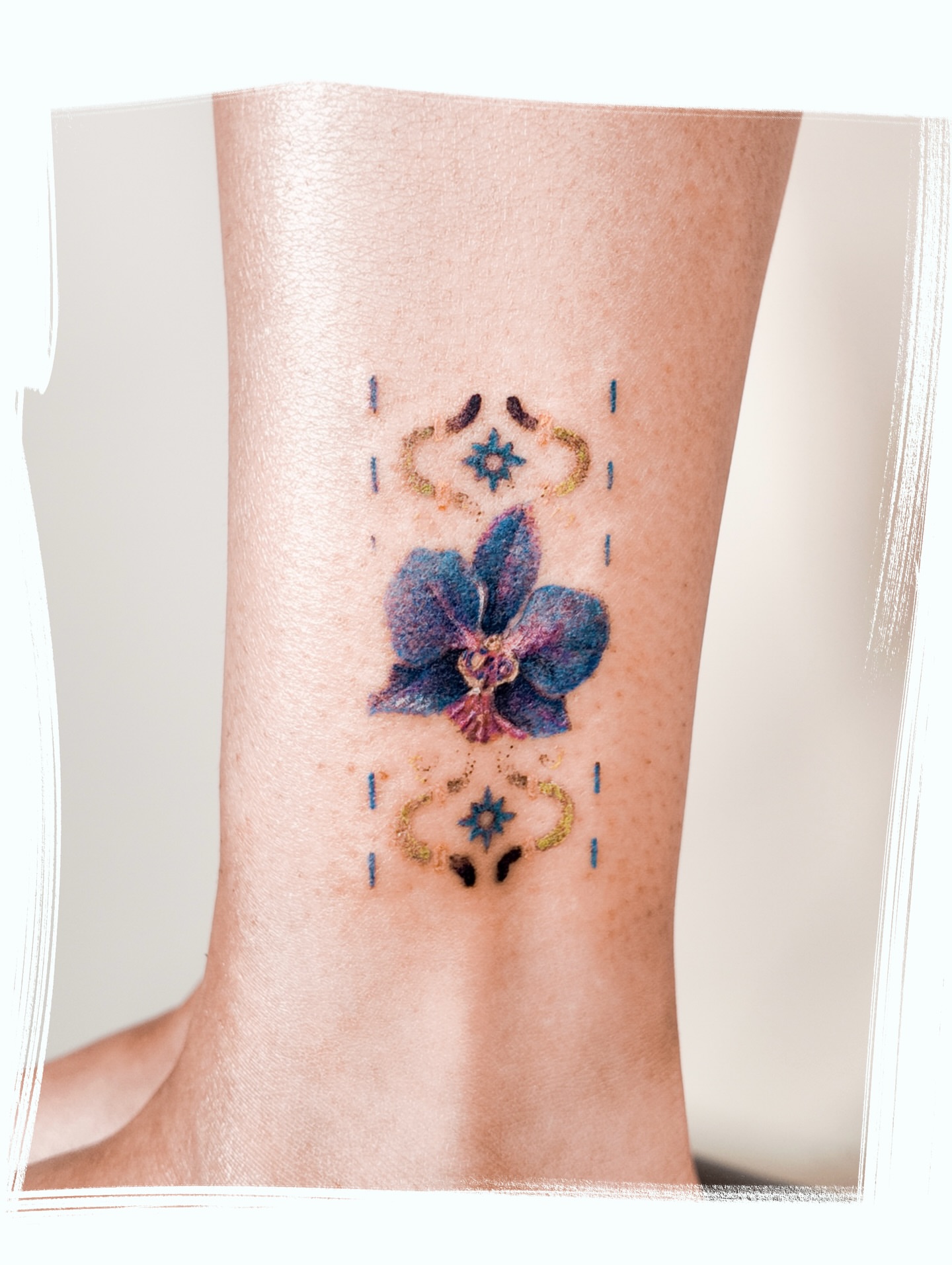Orchid and celestial symbols watercolor tattoo on the calf by Micah Light (color micro realism, Los Angeles, California