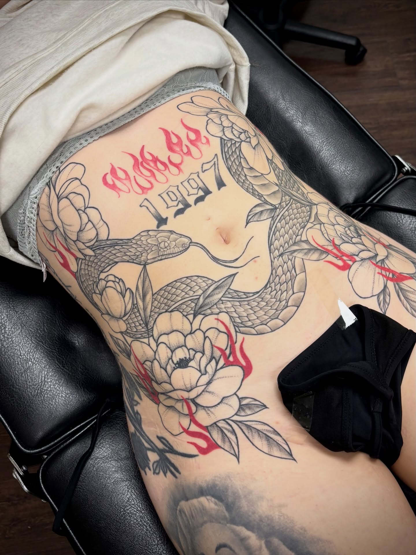 Snake and peony American traditional tattoo on the thigh by sydney honn