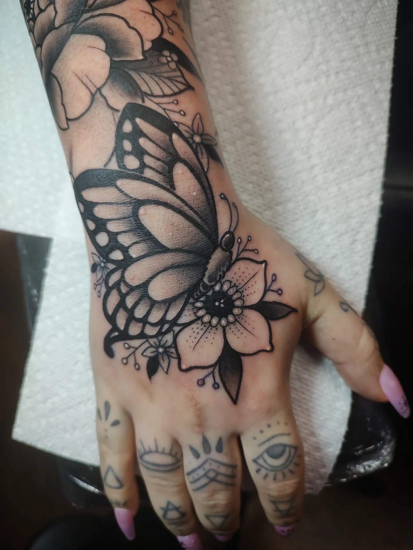 Butterfly and flower black and grey tattoo on the hand by Jennifer Fowler