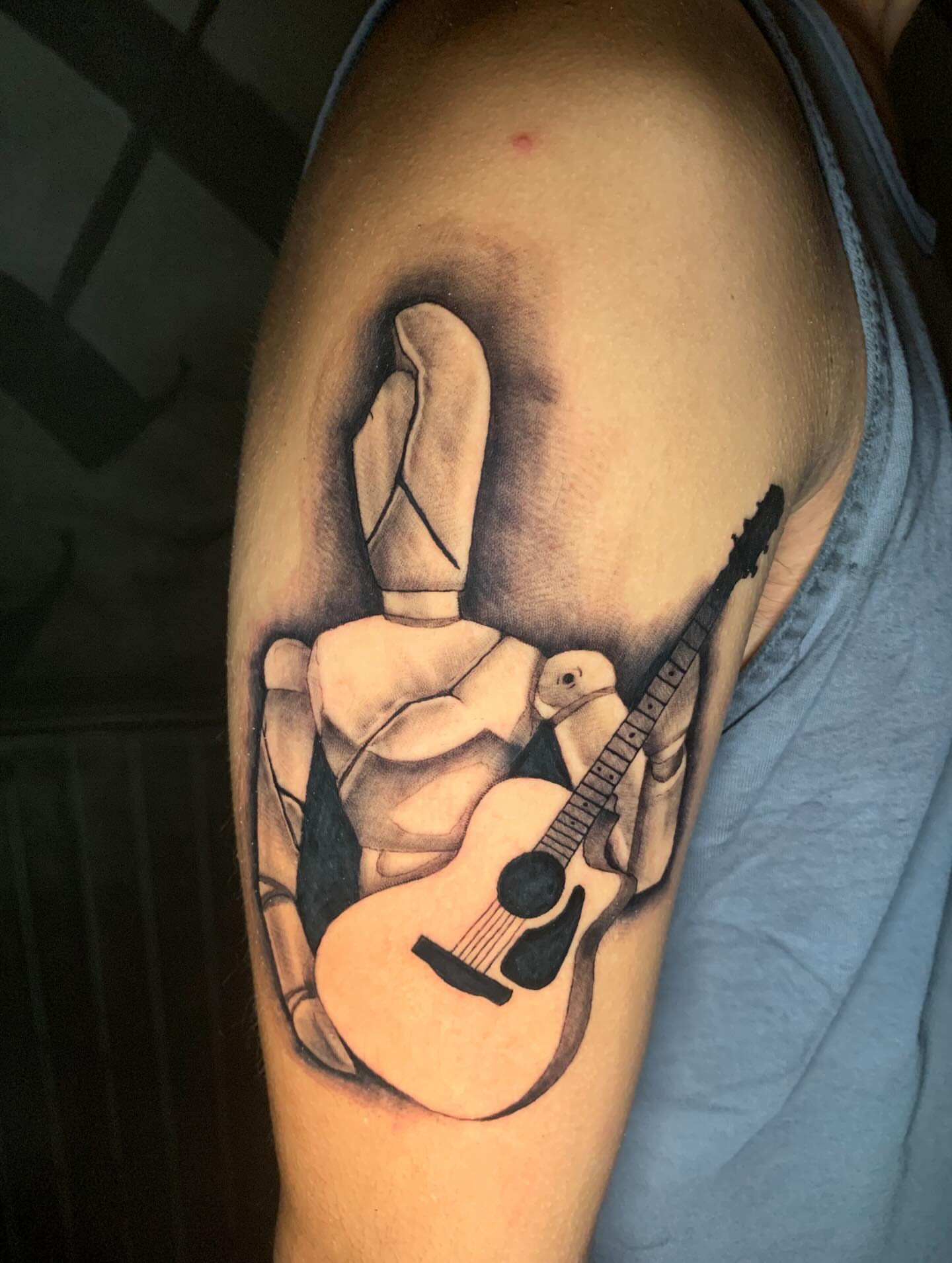 Finger and guitar realism tattoo on the upper arm by Devon