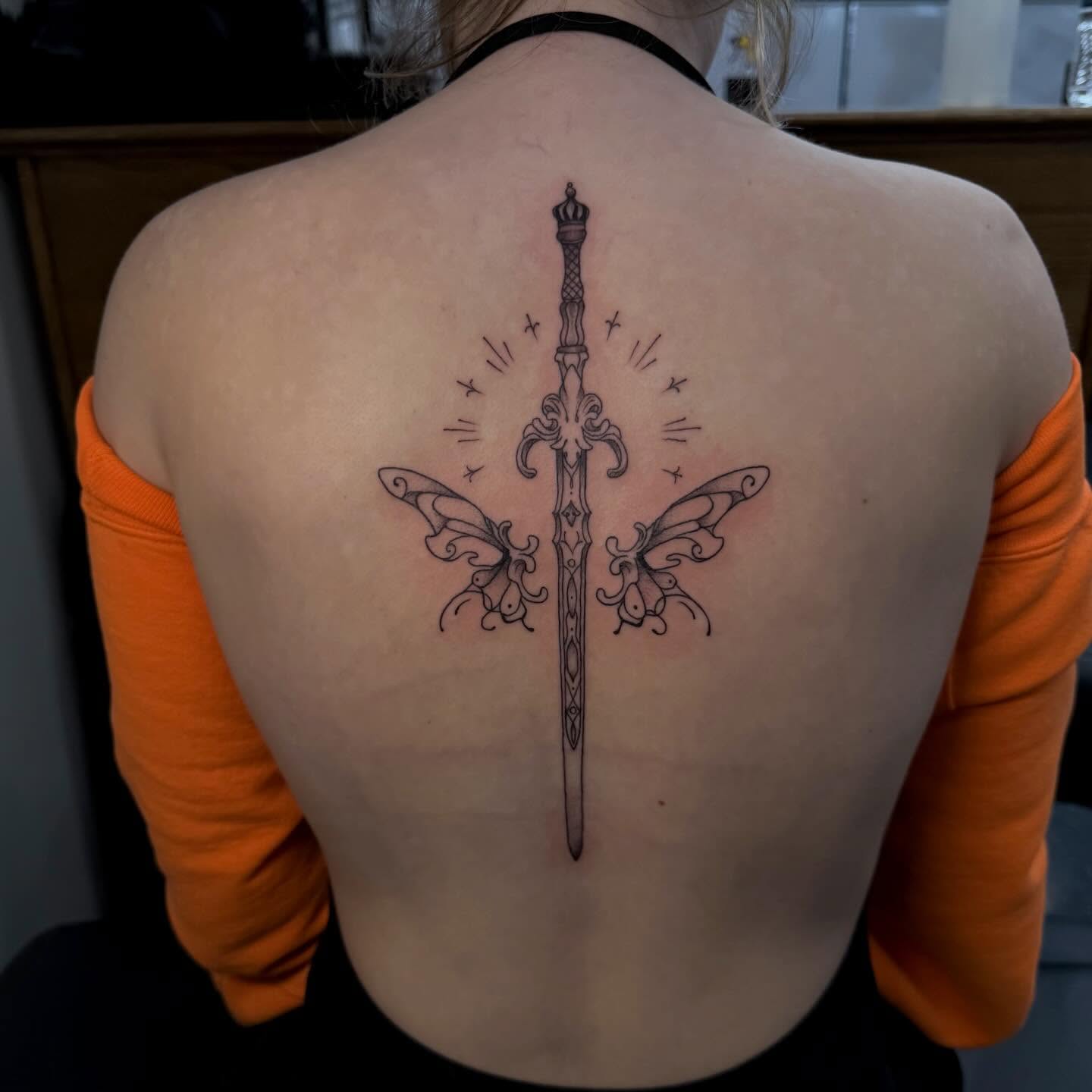 Sword with wings black and grey tattoo on the back by 𝕯𝖆𝖓𝖎