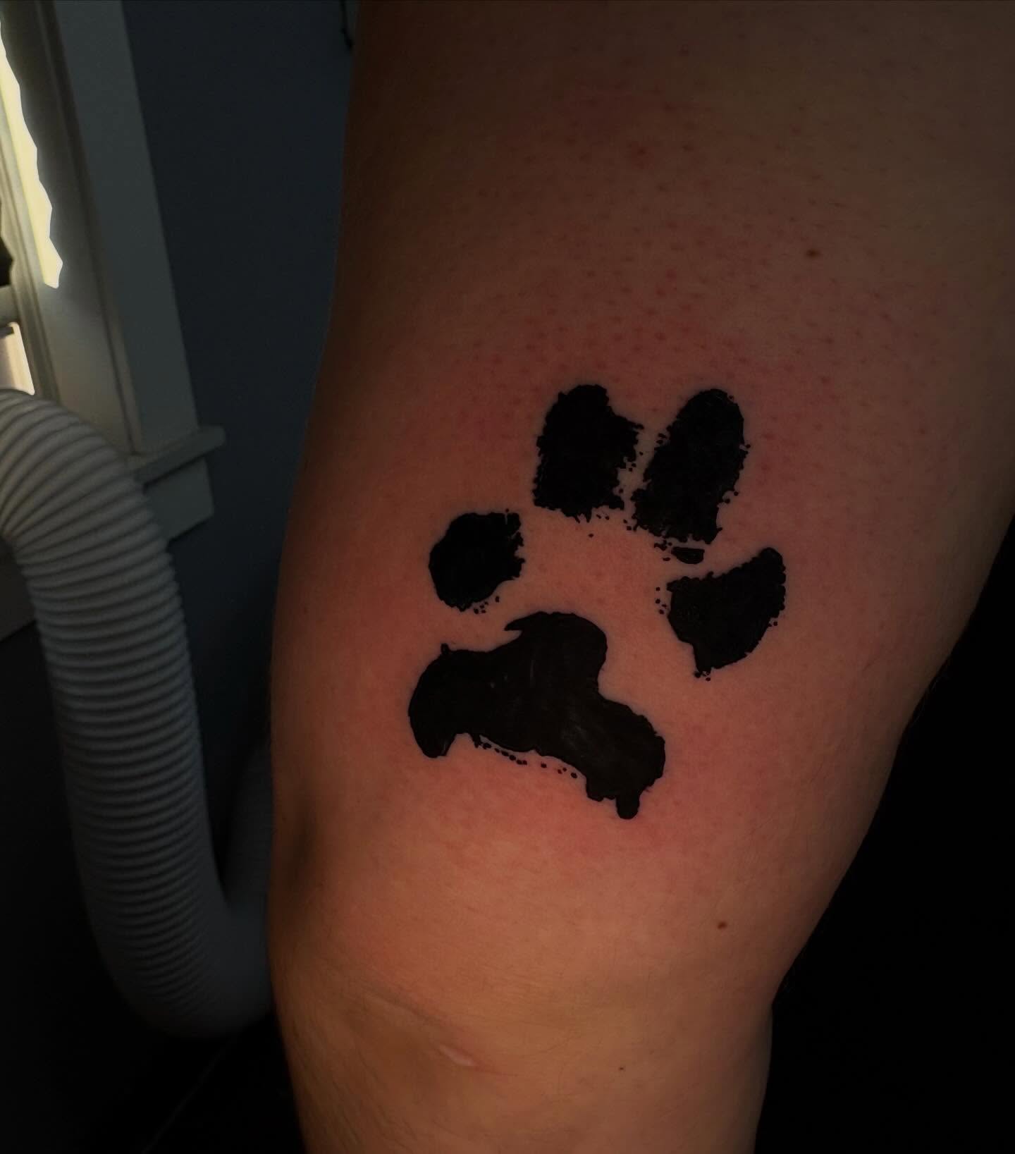 Paw print black and grey tattoo on the thigh by Jenna Clayton