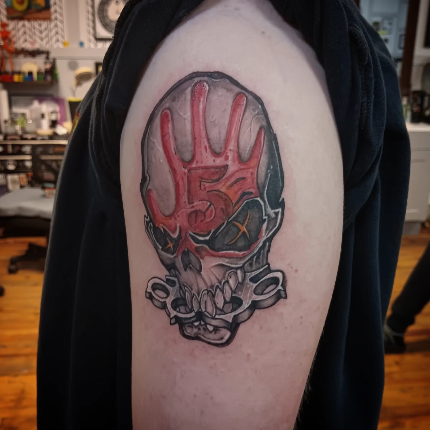 Skull with hand dark realism tattoo on the shoulder by Niki Jackson