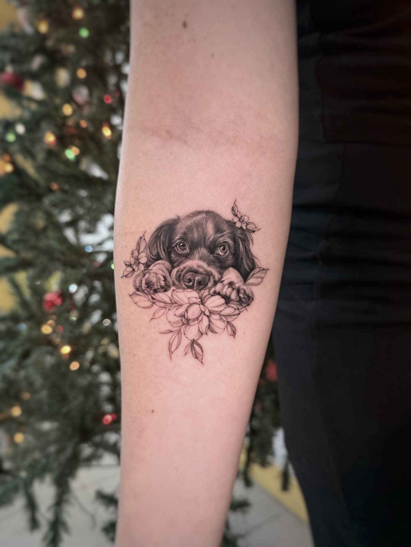 Puppy with flowers realism tattoo on the forearm by Nana