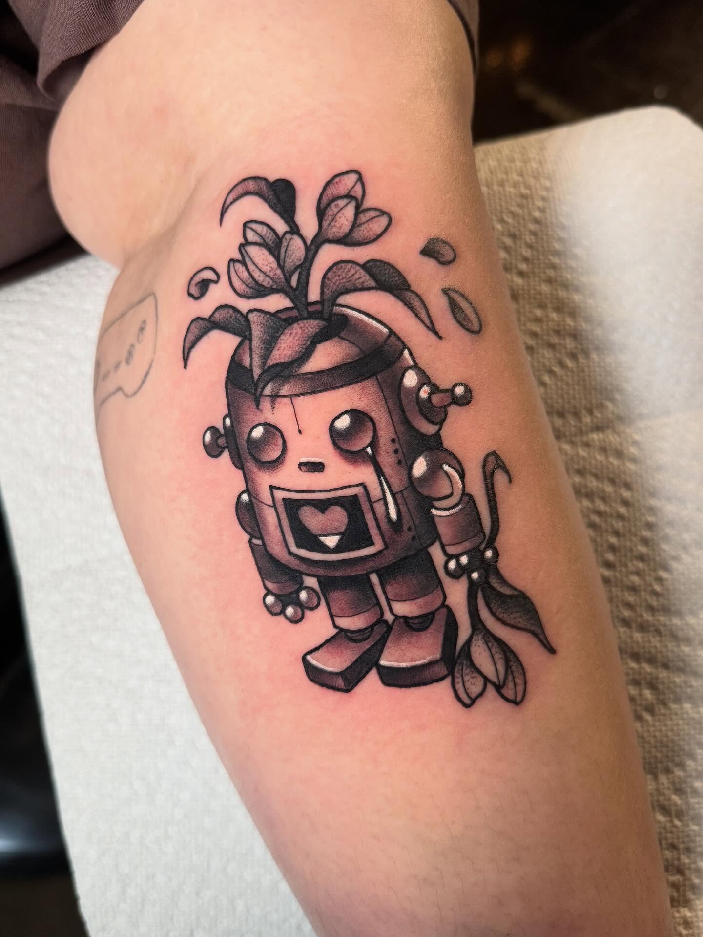 Robot with plant head black and grey tattoo on the forearm by Jess Longfield, Des Moines, Iowa