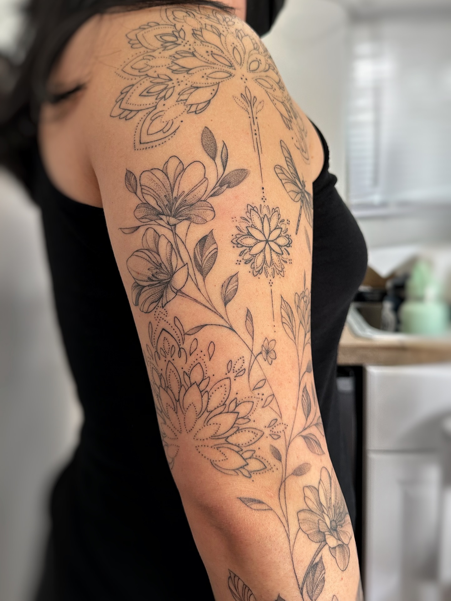 Floral dotwork tattoo on the upper arm by jaclyn park