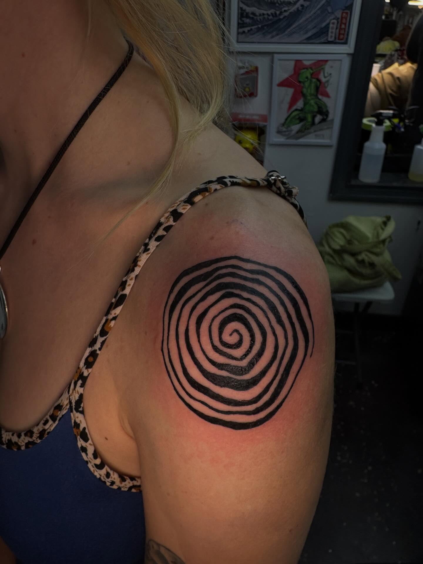 Hypnotic spiral geometric tattoo on the shoulder by Jenna Clayton