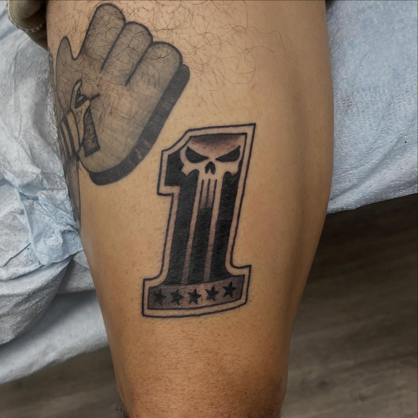 Number one with skull black and grey tattoo on the leg by Franky Sharpz