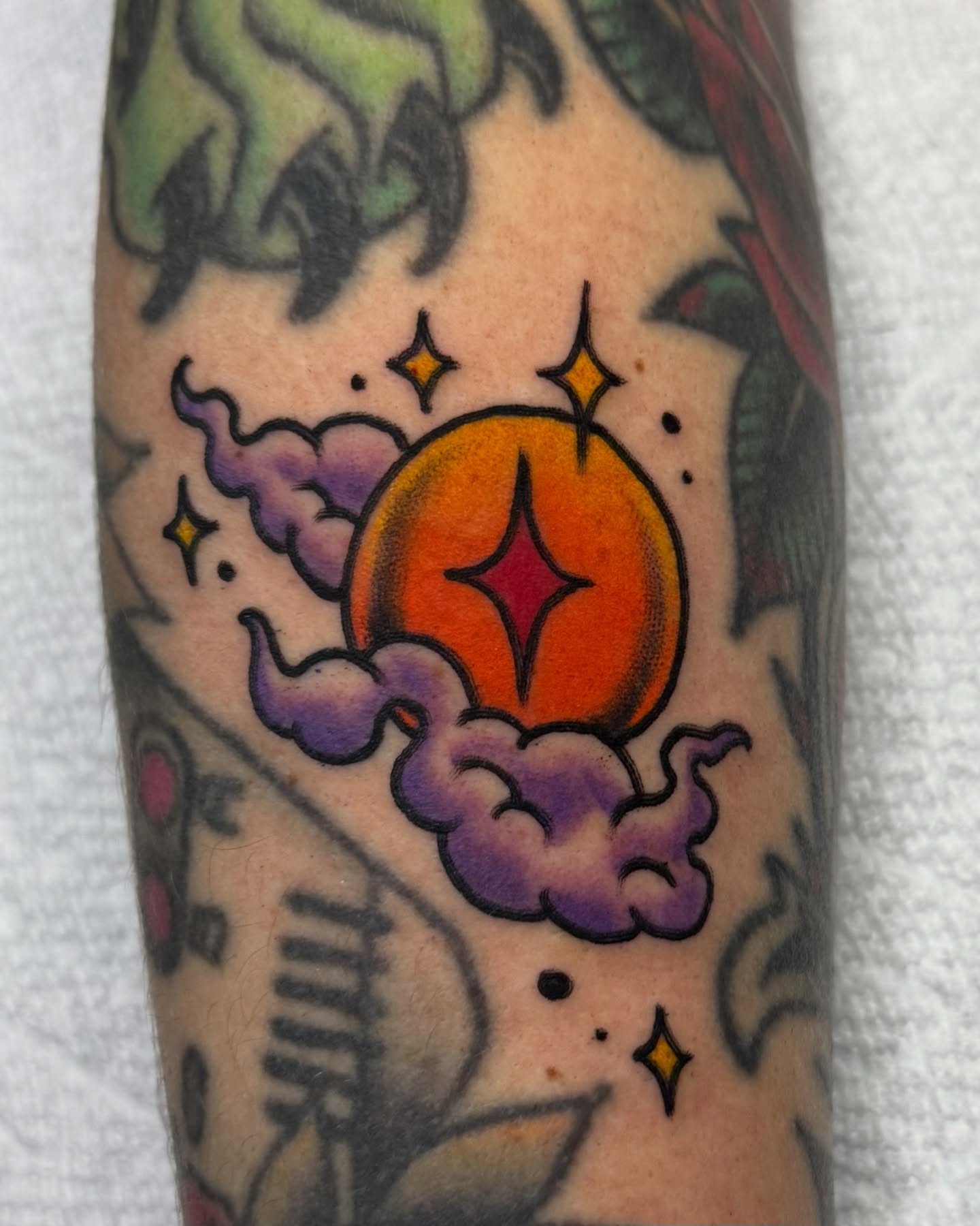 Orange sun with star American traditional tattoo on the forearm by Ash Nicola, Asheville, North Carolina