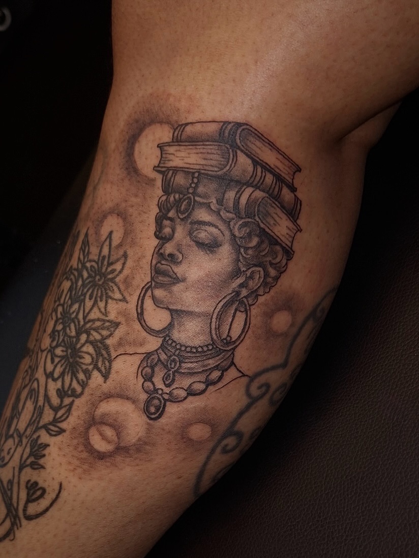 Woman with books on head tattoo on the forearm by InkDex Collective