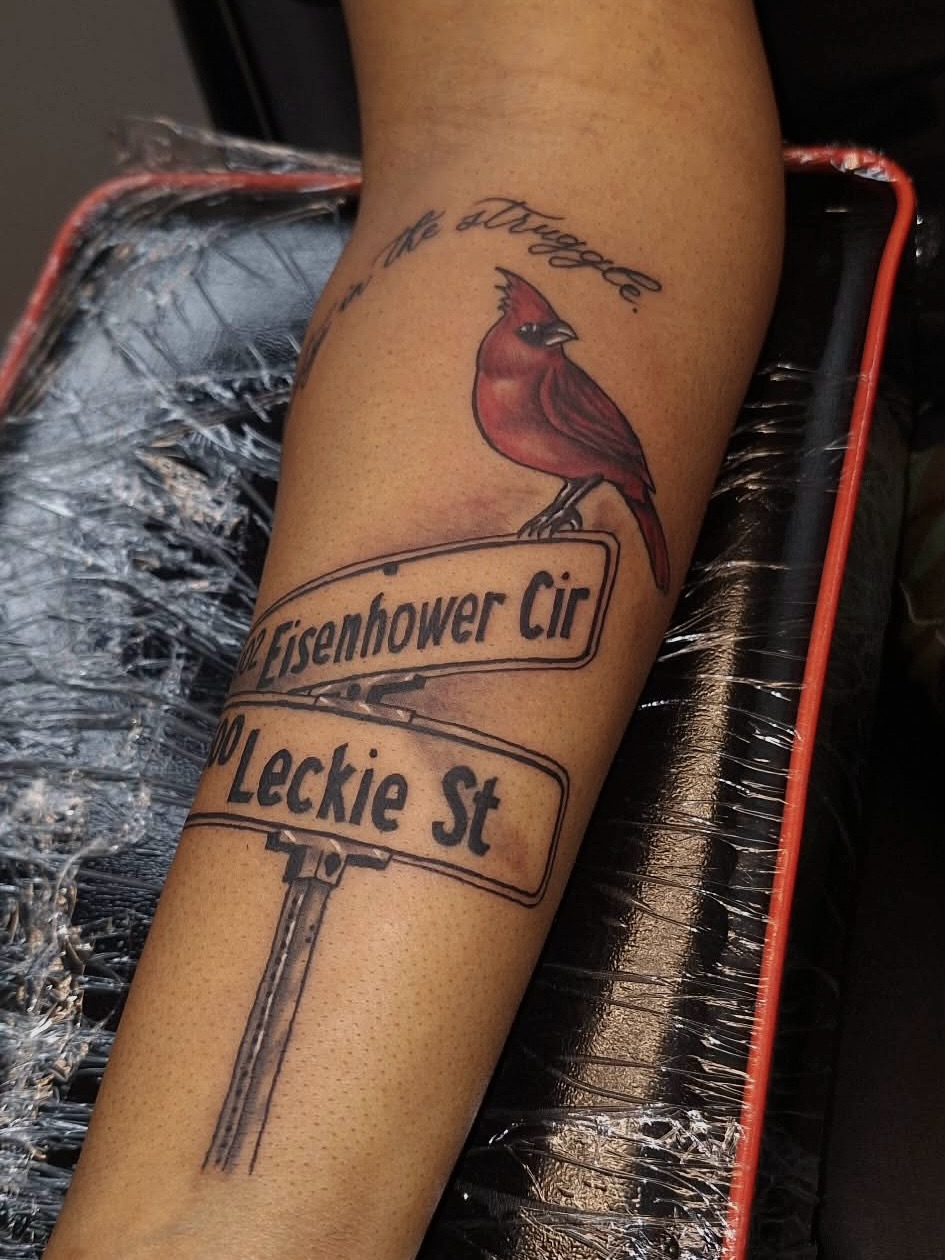 Cardinal on street signs with lettering tattoo on the forearm by InkDex Collective
