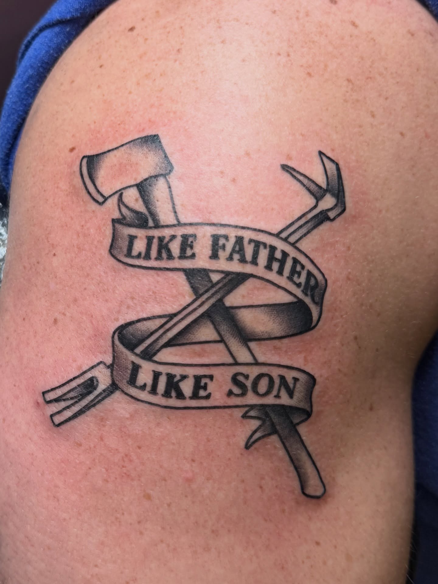 Axe and hammer crossed with banner black and grey tattoo on the shoulder by Gilberto Flores Nava