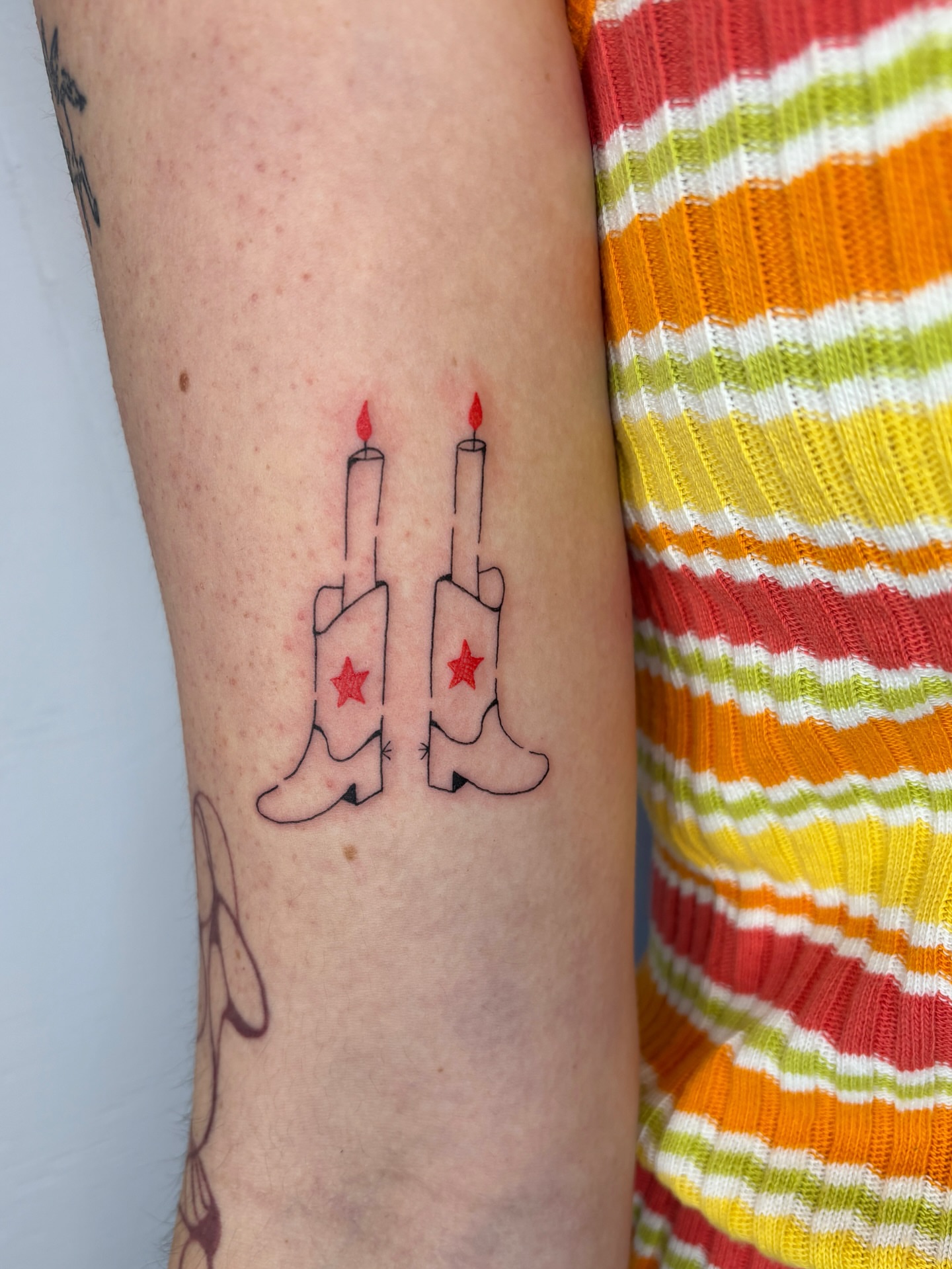 Cowboy boots with candles geometric tattoo on the forearm by Raye