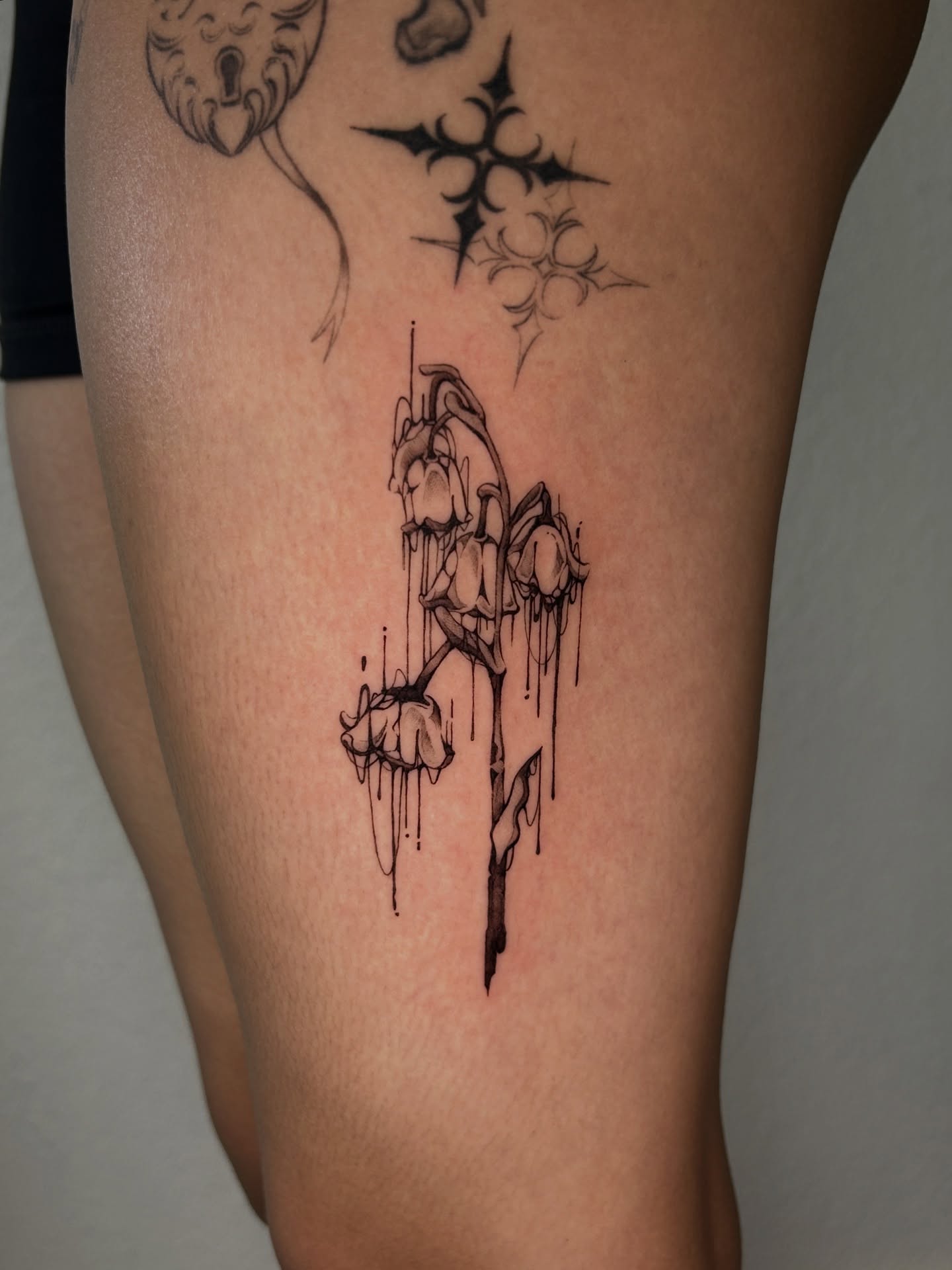 Dripping flowers black and grey tattoo on the thigh by Miri